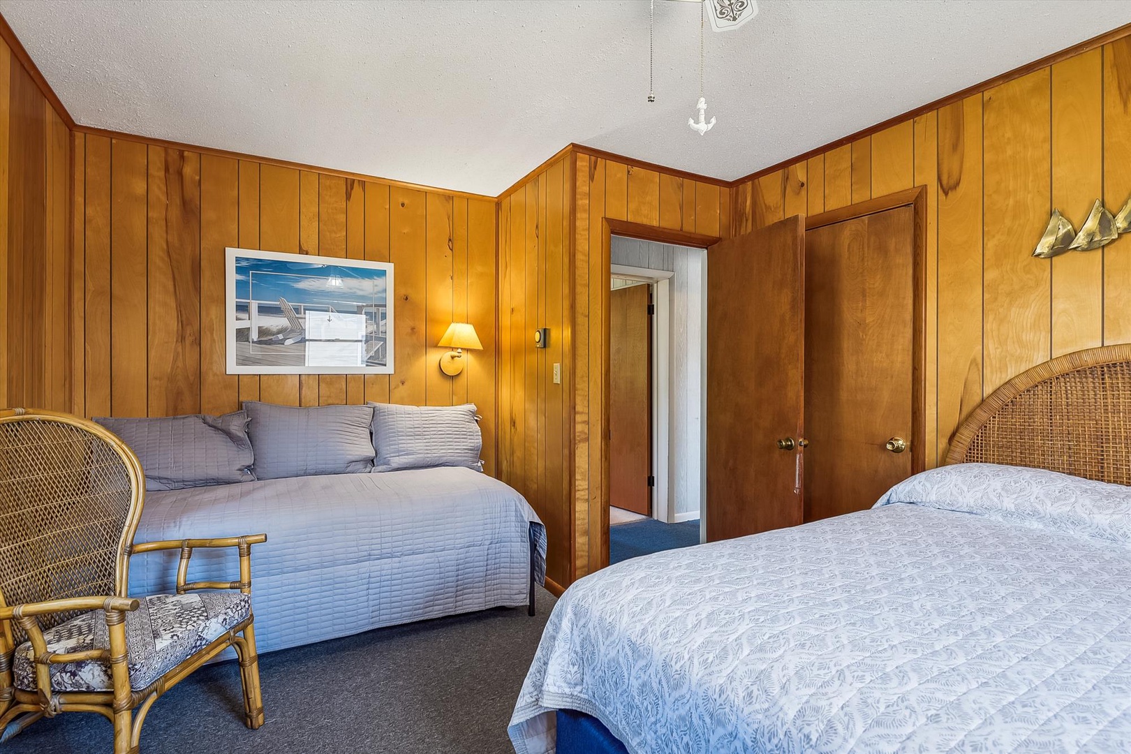 Unwind in your cozy retreat with two comfortable beds, warm wood-paneled walls, and a nautical touch that sets the perfect seaside escape mood.