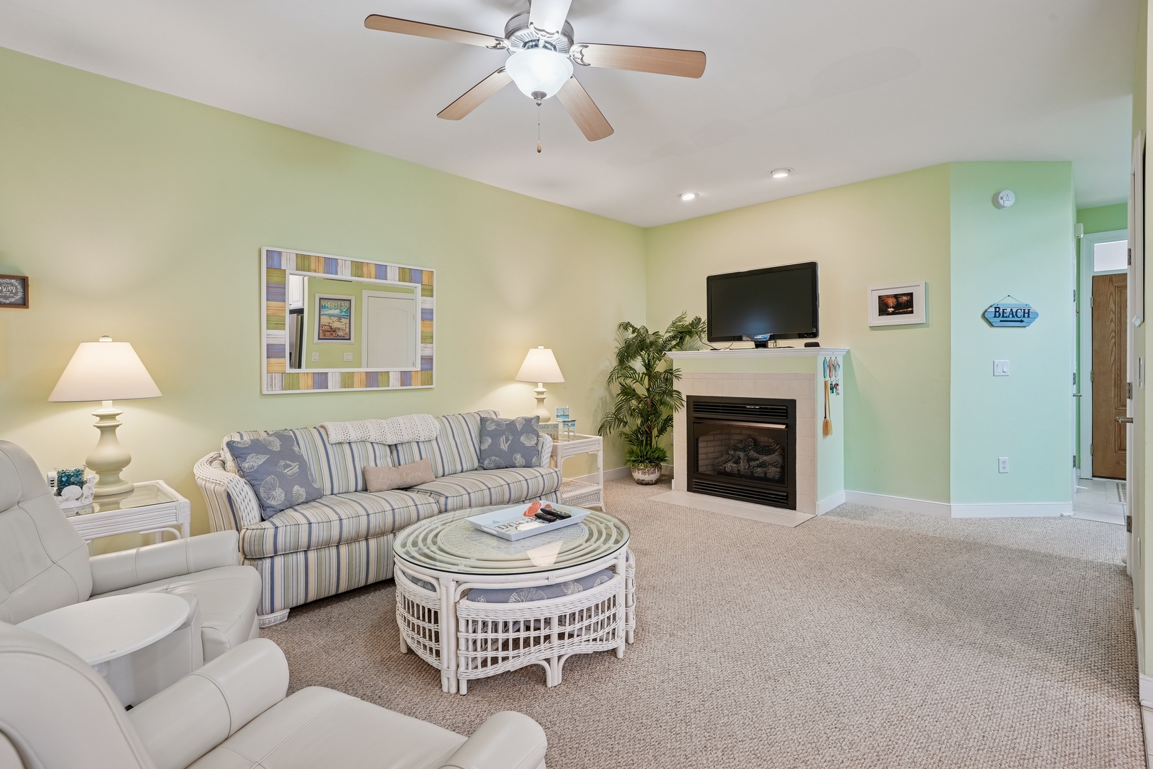 Unwind in your cozy living room with coastal-themed décor, ceiling fan comfort, and a warm fireplace for perfect relaxation.