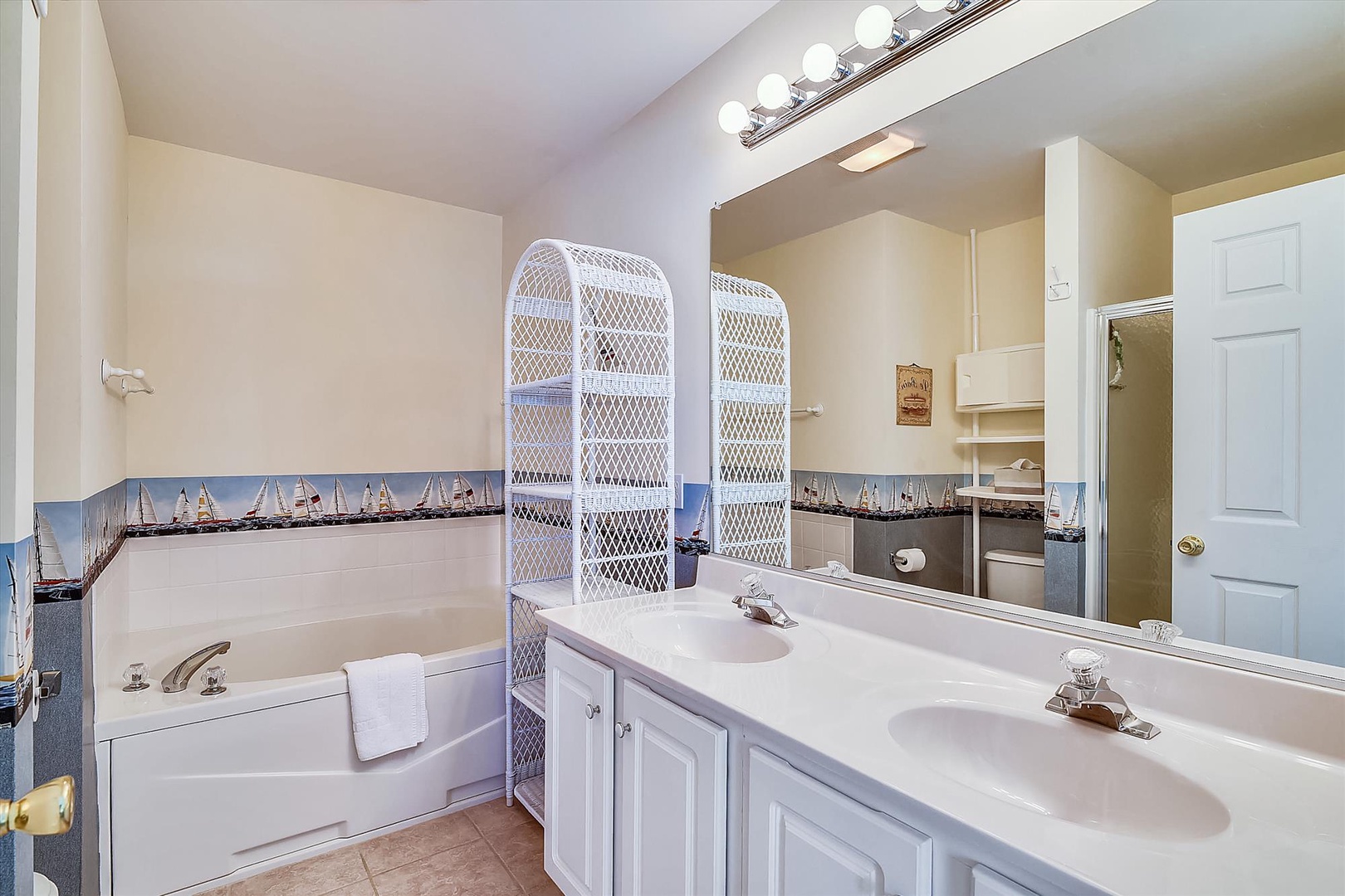 Your private bathroom features a soaking tub, dual vanities with ample counter space, and cheerful nautical touches that set a breezy, coastal mood for your stay.