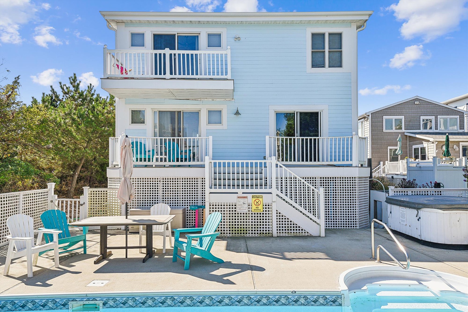 A breezy beach house offering waterside comfort with two private balconies, outdoor seating, and a sparkling pool for sunny days.