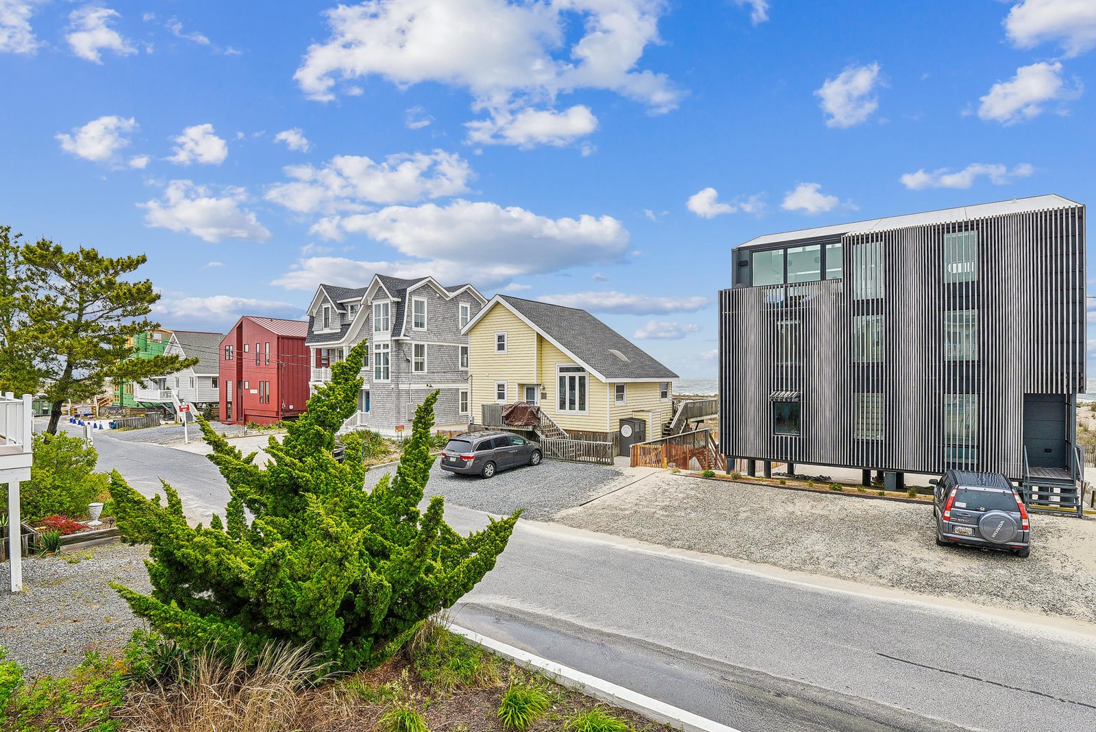 A modern beachside property set in a coastal neighborhood, featuring distinctive architecture and convenient parking alongside nearby homes.