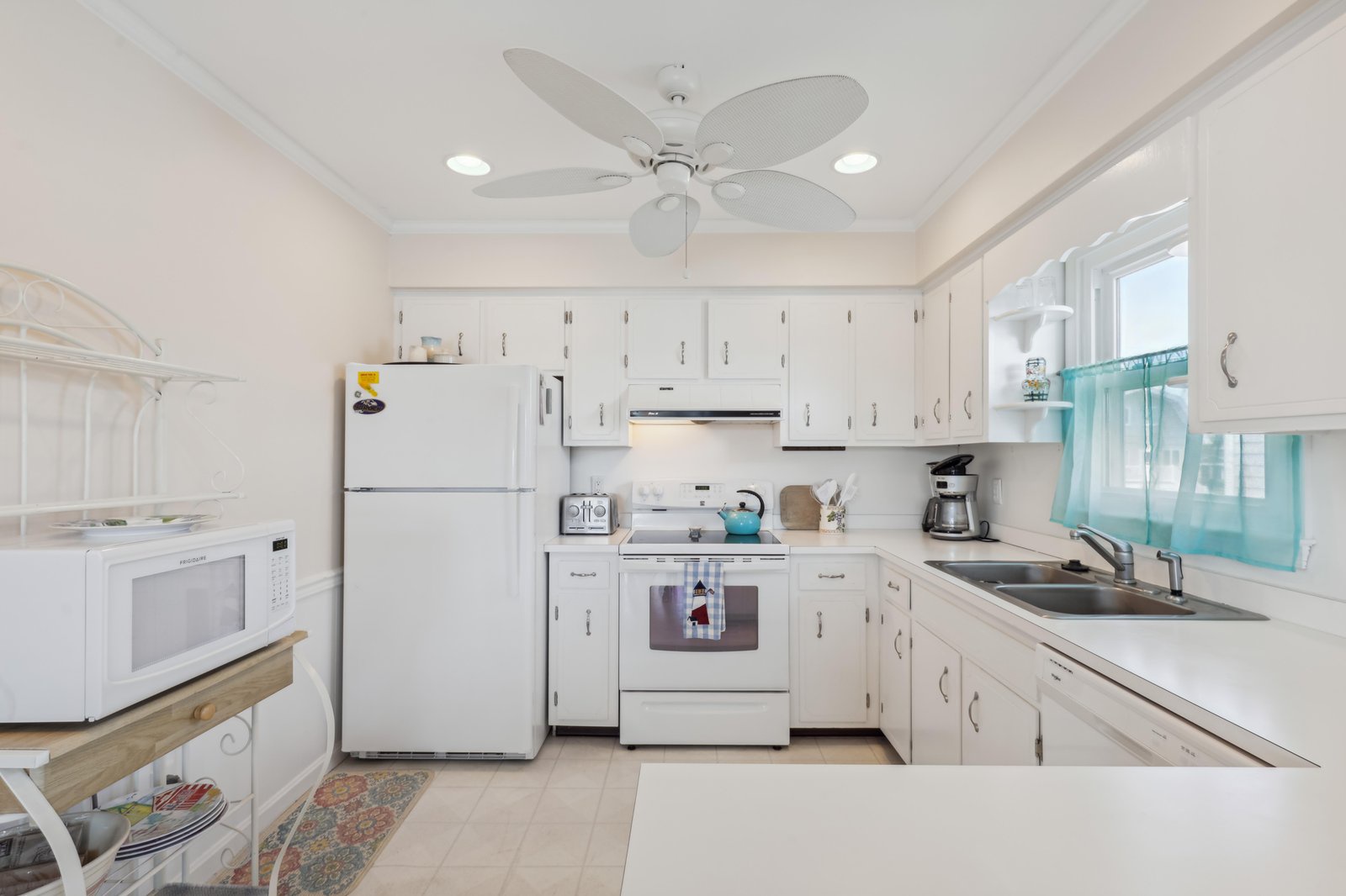 Your bright, fully equipped kitchen invites you to prepare meals with ease—white cabinetry, modern appliances, and a ceiling fan create a welcoming space to gather and cook.