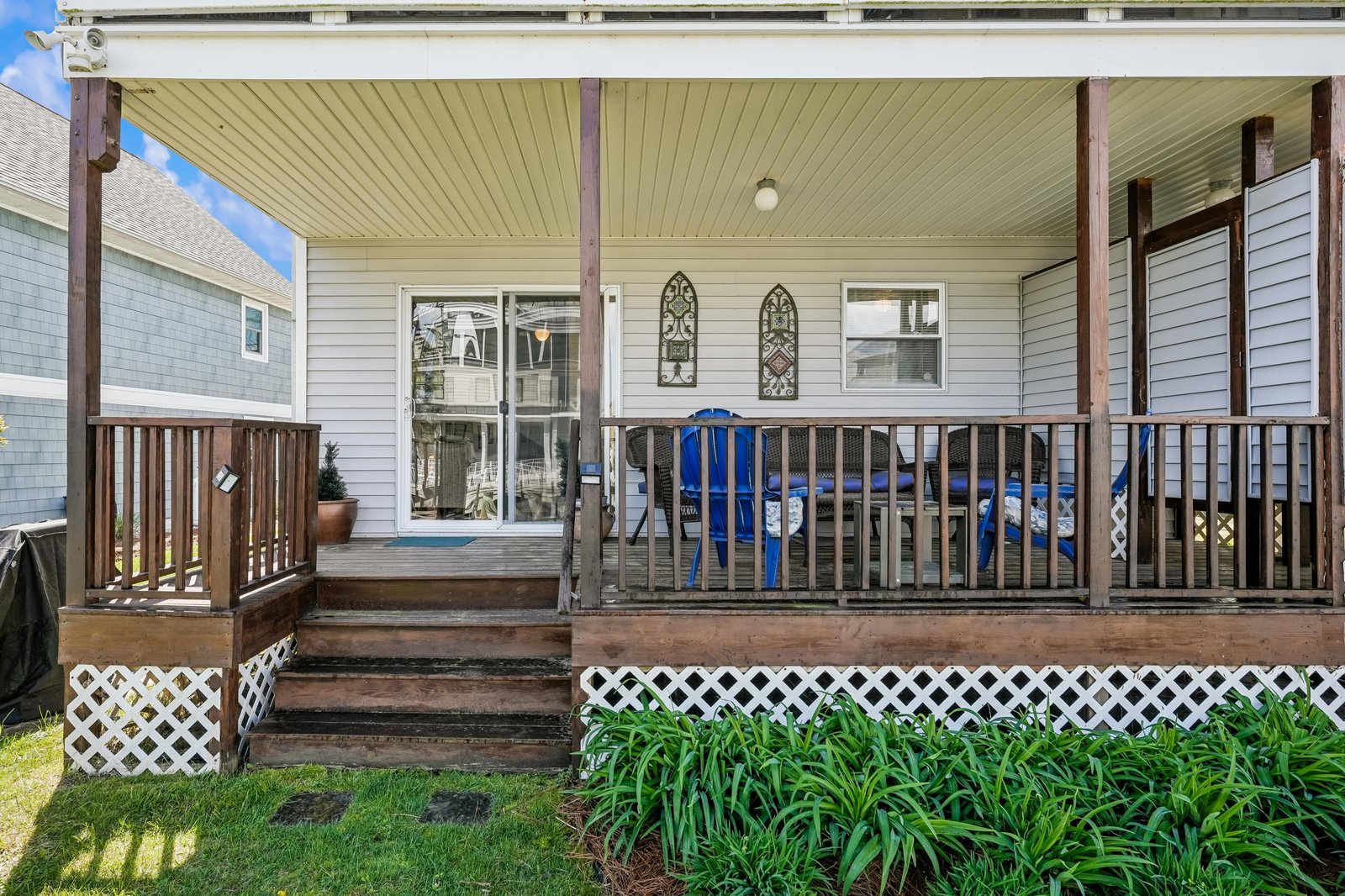 A covered porch features wood steps, decorative metal railings, and peaceful garden views—your private entryway to relax and unwind after exploring the area.