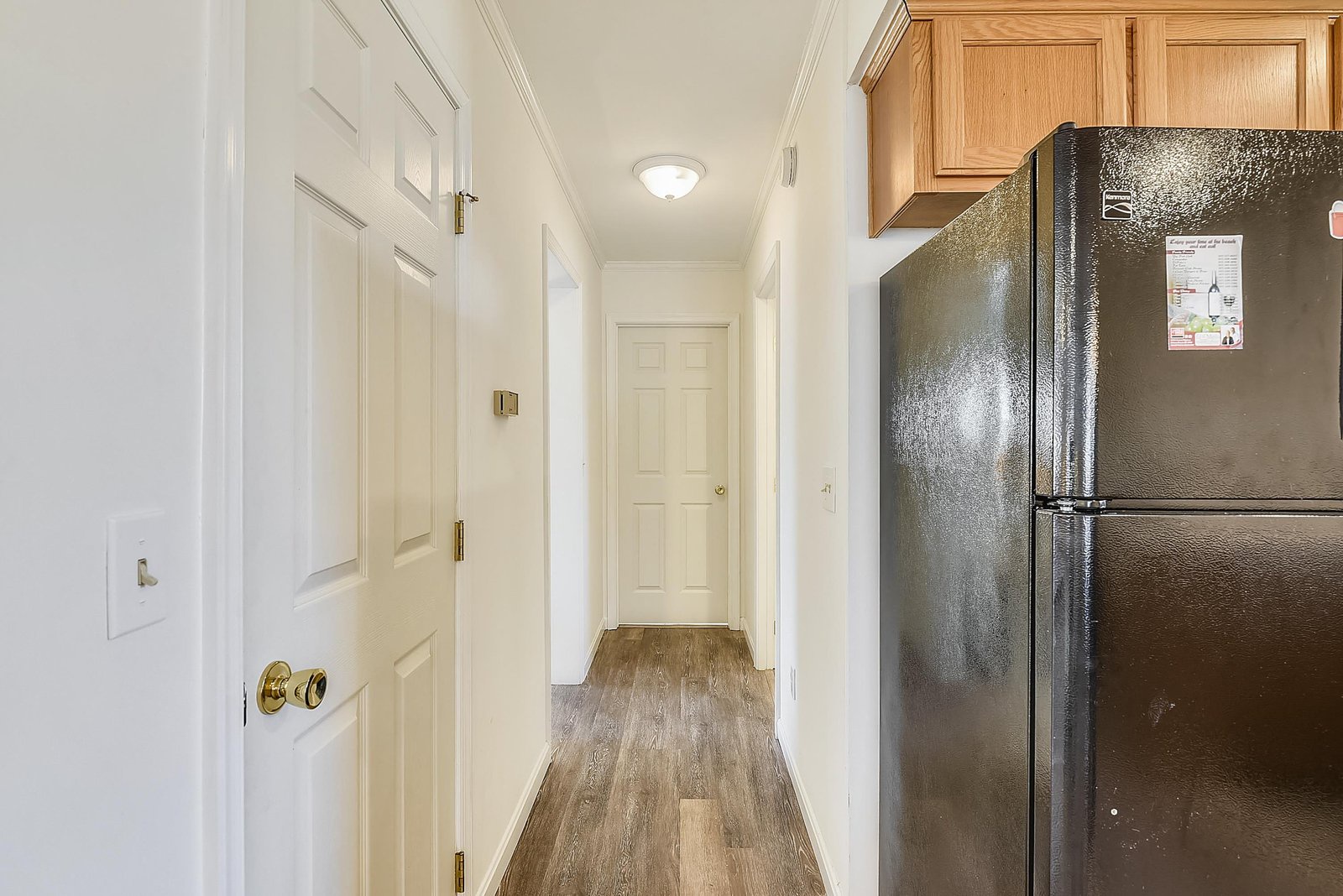 A clean hallway with warm wood flooring connects your rooms. Full-sized appliances and natural wood cabinetry bring comfort and convenience to your stay.