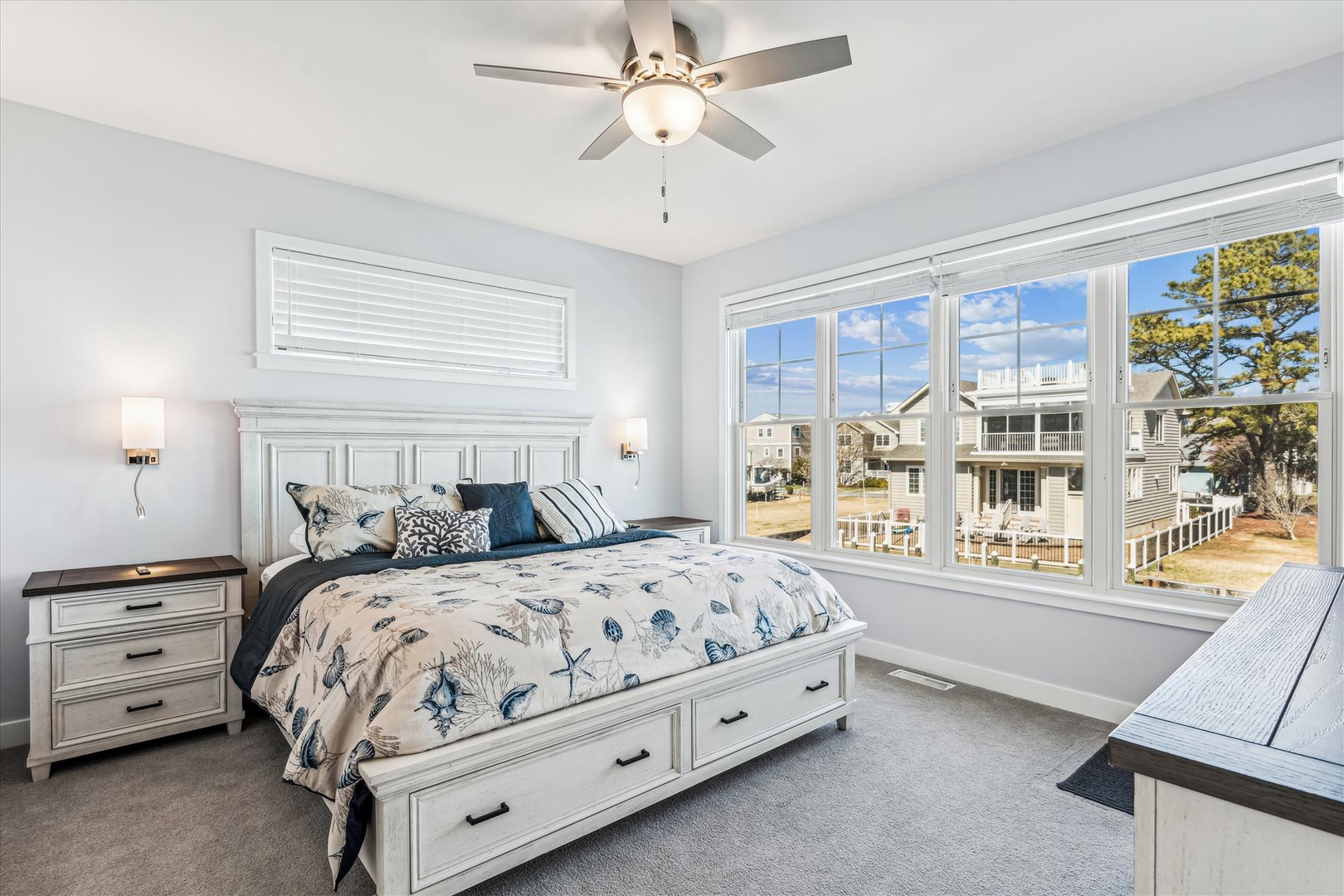 Drift off in this serene coastal bedroom where soft nautical accents and crisp white furnishings create a peaceful retreat. Natural light floods the space through expansive windows, while the ceiling fan keeps you comfortable year-round.