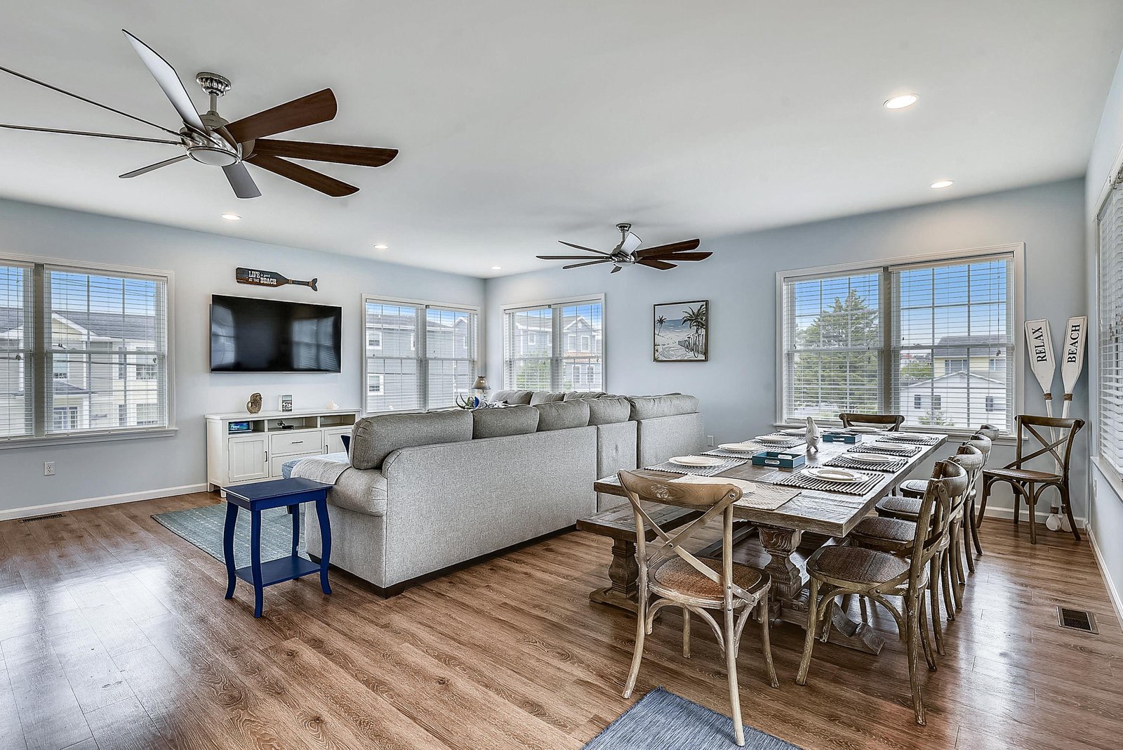Gather around this spacious open-plan living and dining area, where high ceilings, cool ceiling fans, and abundant natural light create a breezy, relaxed atmosphere perfect for your beach getaway.