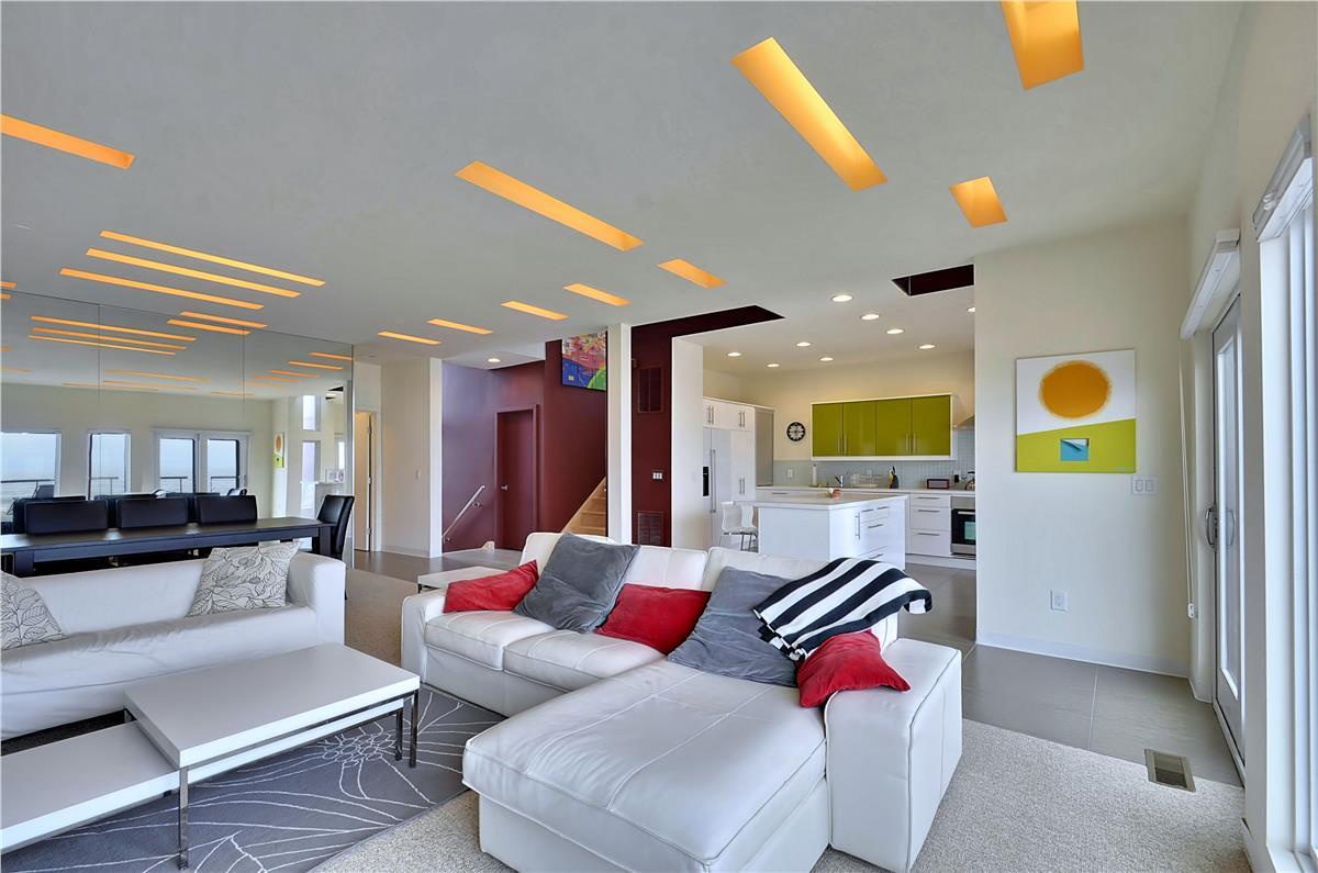Relax in this stunning open-concept living space where modern design meets comfort. Sink into the plush sectional and admire the artistic ceiling lighting, while the sleek kitchen invites you to prepare meals with ocean breezes flowing through.