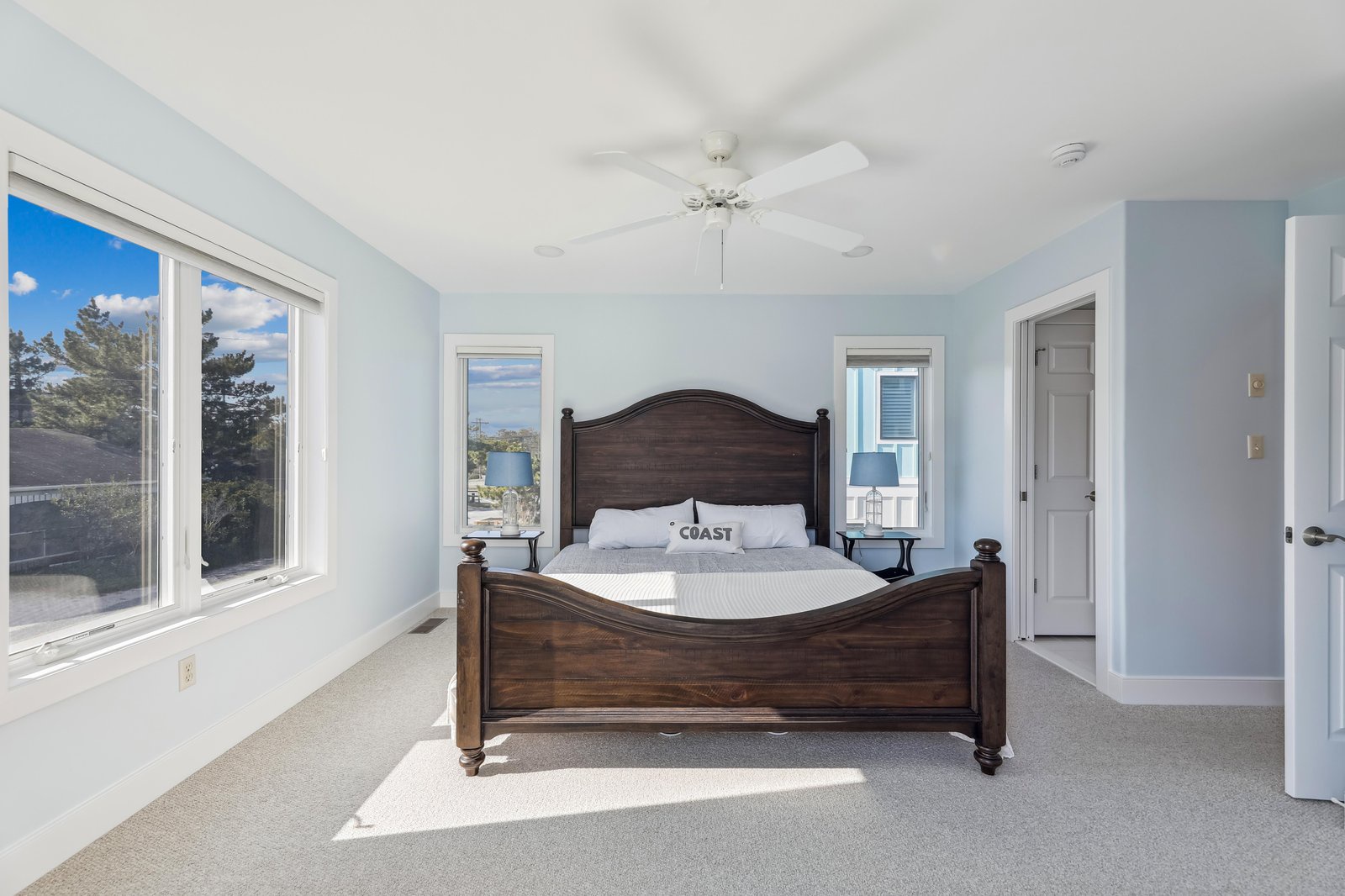 Drift off to sleep with natural light streaming through large windows and a gentle coastal breeze from the ceiling fan above your comfortable bed.