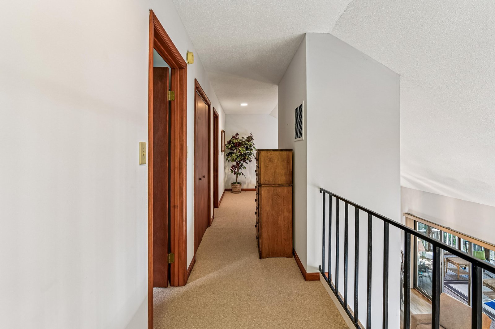 A quiet upstairs hallway with warm wood doors and soft carpet underfoot leads you to your private retreat—simple, inviting, and ready to welcome you home after a day of adventure.