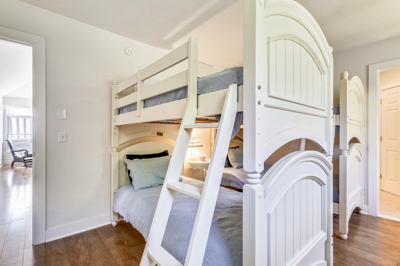Your kids will love this charming bunk room with its elegant white beds and cozy bedding—a perfect retreat for little adventurers after a day of exploring together.