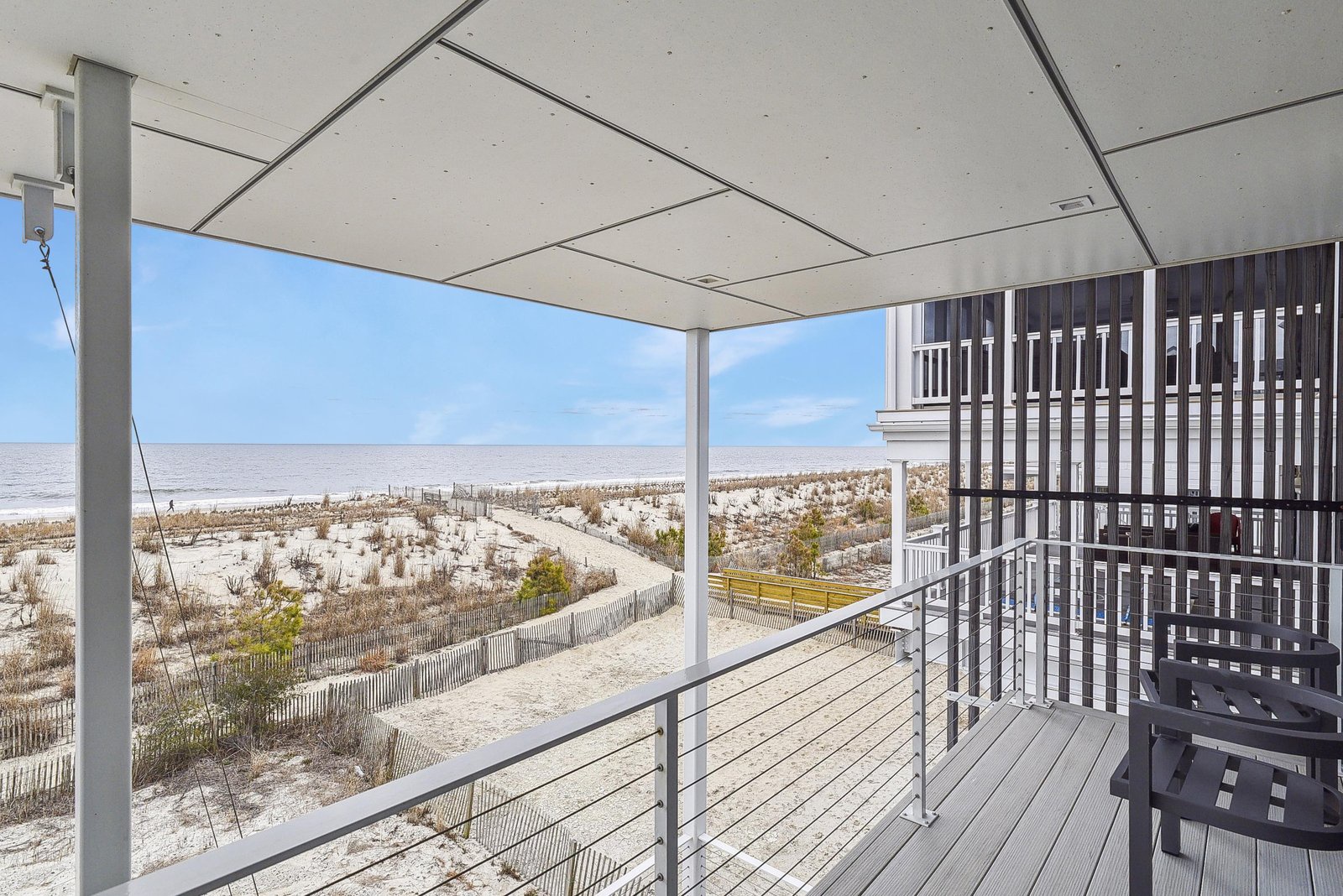 A covered balcony overlooks soft sand dunes and the open ocean beyond. You'll feel the coastal breeze while soaking in tranquil beachfront views from your own outdoor retreat.
