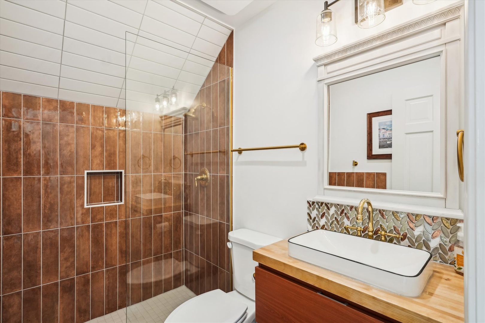 Step into your private bathroom, where warm terracotta tiles and artisan leaf-pattern accents create a spa-like retreat. The spacious walk-in shower and elegant vanity invite you to unwind after exploring the area.