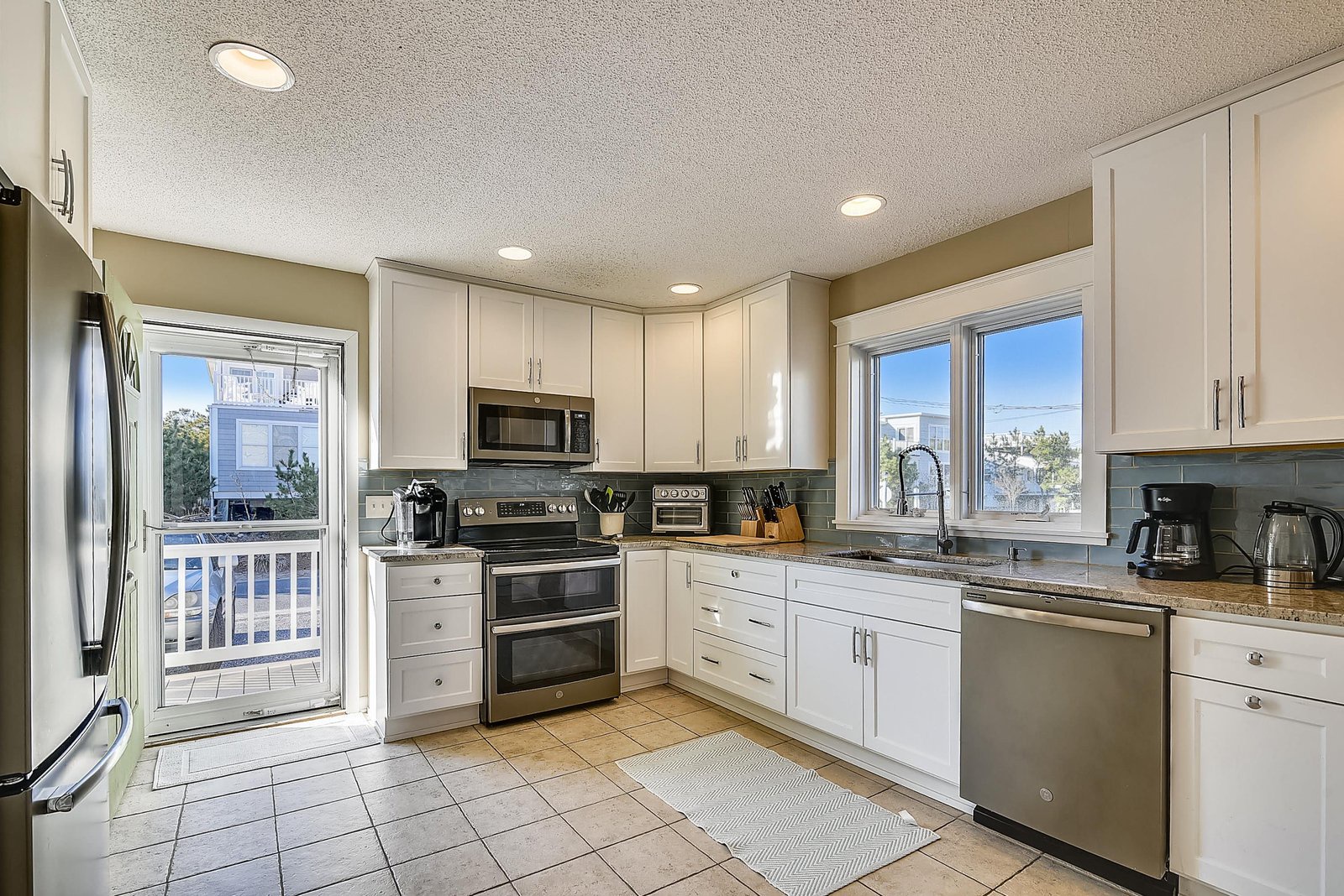 Picture yourself preparing meals in this bright, fully equipped kitchen with stainless steel appliances and ample counter space. Sunlight streams through large windows, making every moment here feel fresh and inviting.