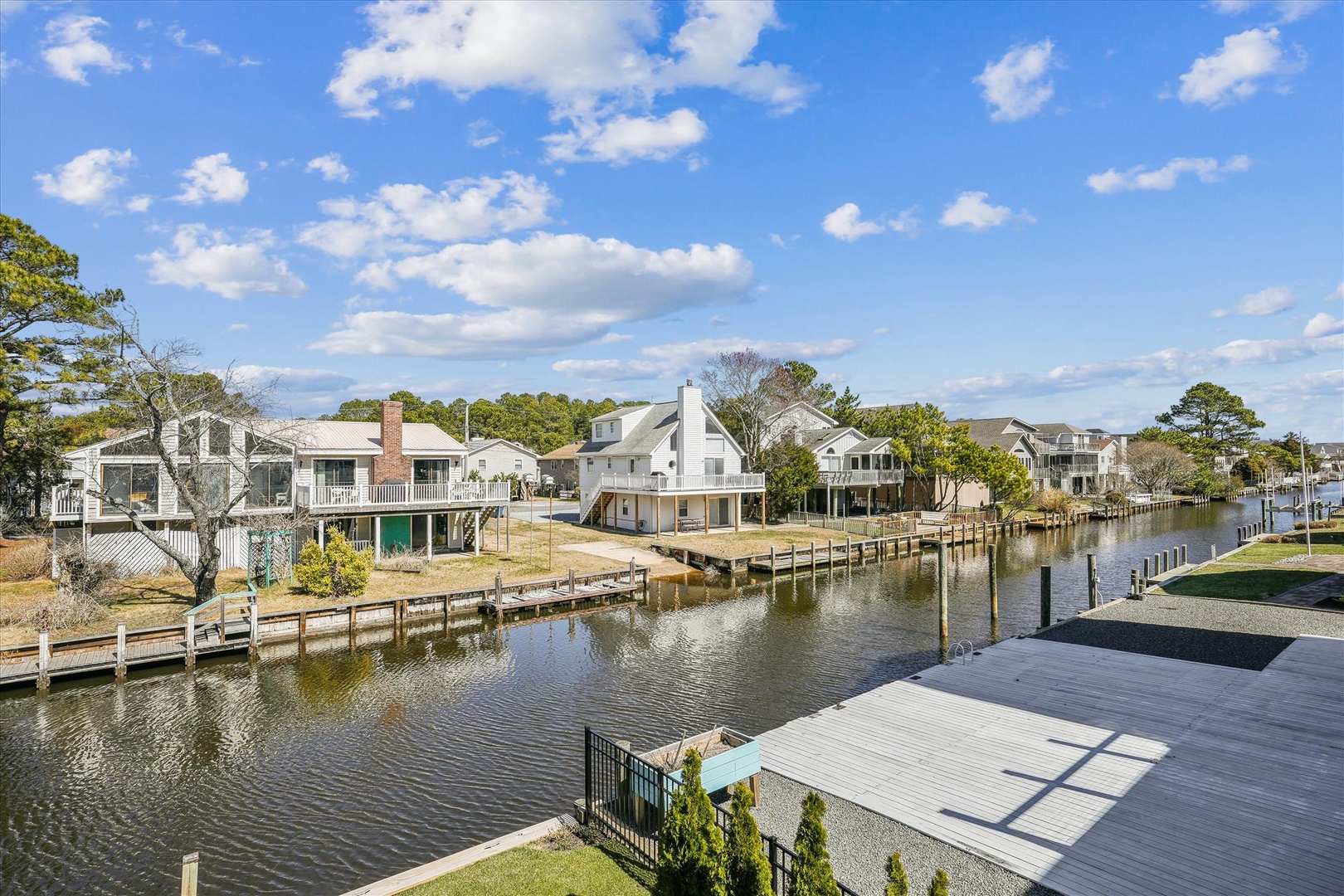 Waterfront community with private docks lining a peaceful canal, surrounded by coastal homes and natural landscaping under blue skies.