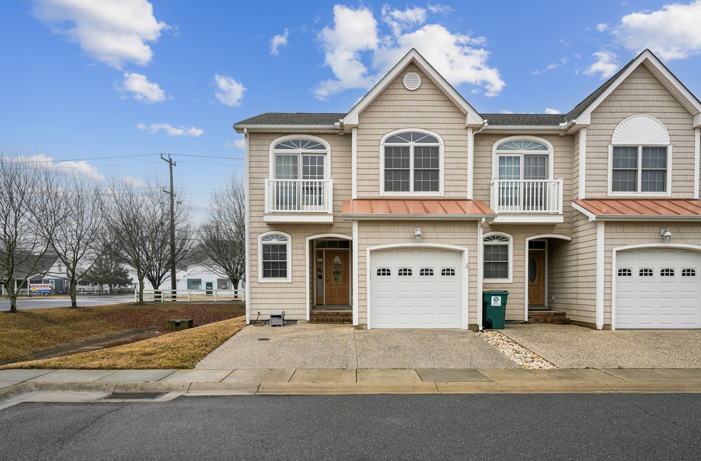 Modern townhome exterior featuring classic shingle siding and welcoming front entrance with convenient parking.