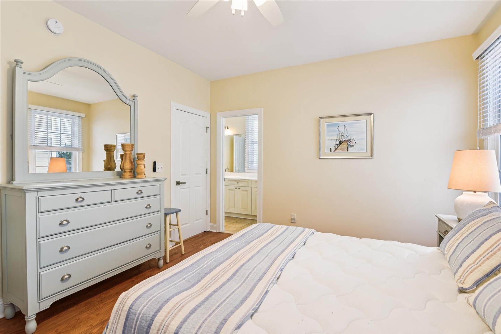 Sink into soft linens and coastal charm in this serene bedroom, where warm yellow tones and nautical touches create your peaceful retreat after beach-filled days.