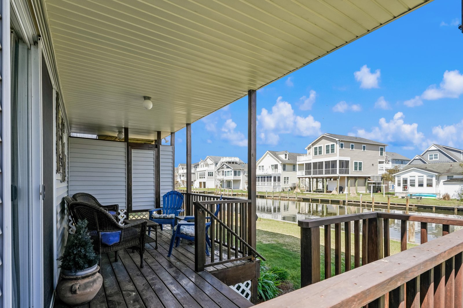 Covered deck overlooking tranquil waterfront neighborhood with cozy seating for morning coffee or evening sunsets. Perfect spot to unwind and soak in peaceful canal views.