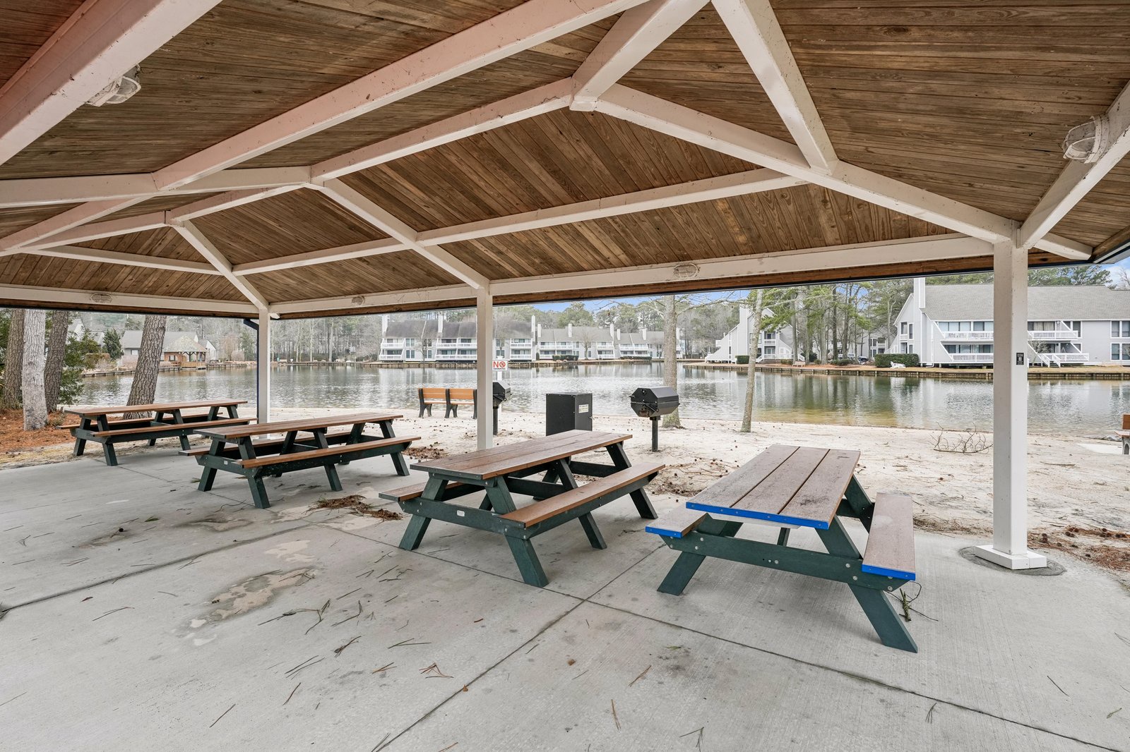 A covered outdoor pavilion offers picnic tables and grilling area overlooking a tranquil lake and surrounding residential community—perfect for family meals or relaxing afternoons by the water.
