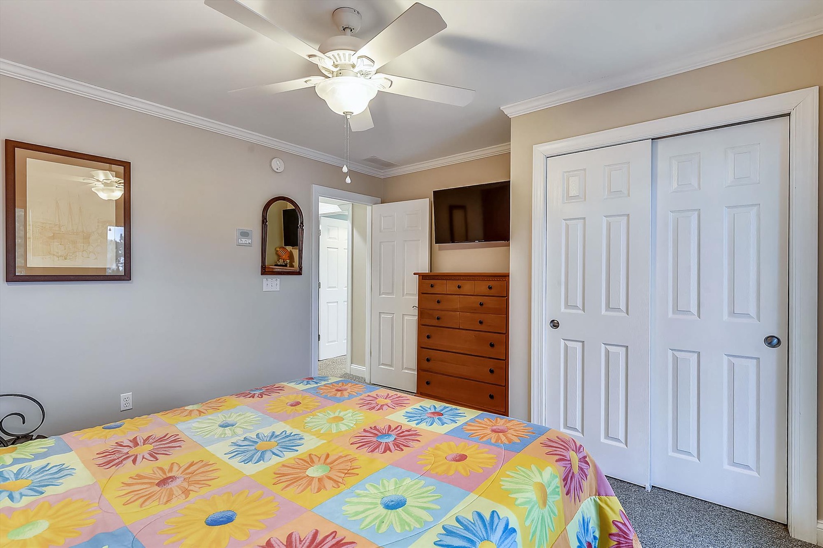 Your comfortable bedroom features a ceiling fan, ample closet space, and a dresser with a flat-screen TV, blending convenience with homey charm for a restful stay.