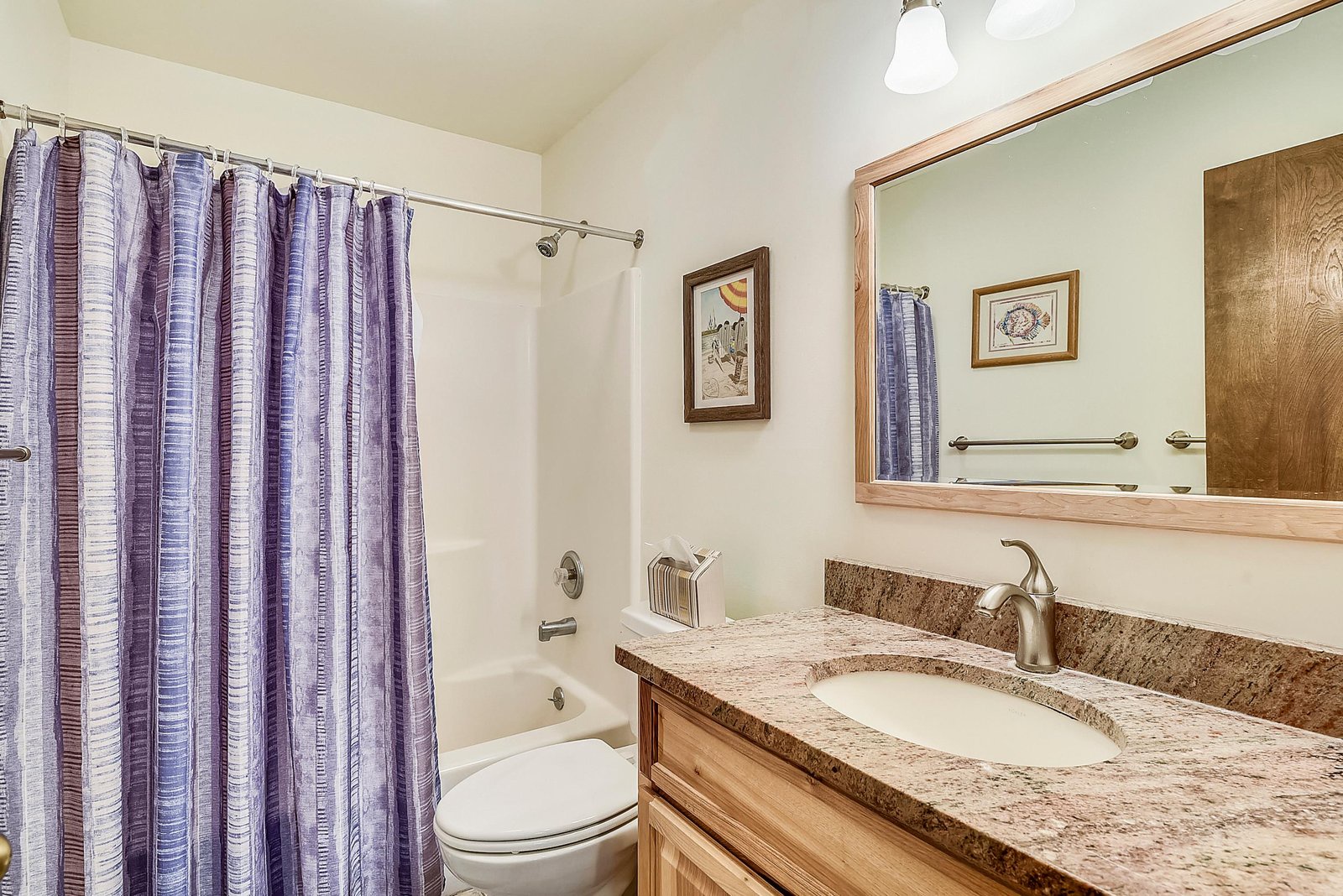 Step into your private bathroom, where natural light filters through soft curtains and a granite vanity with warm wood cabinetry creates a spa-like retreat after your mountain adventures.