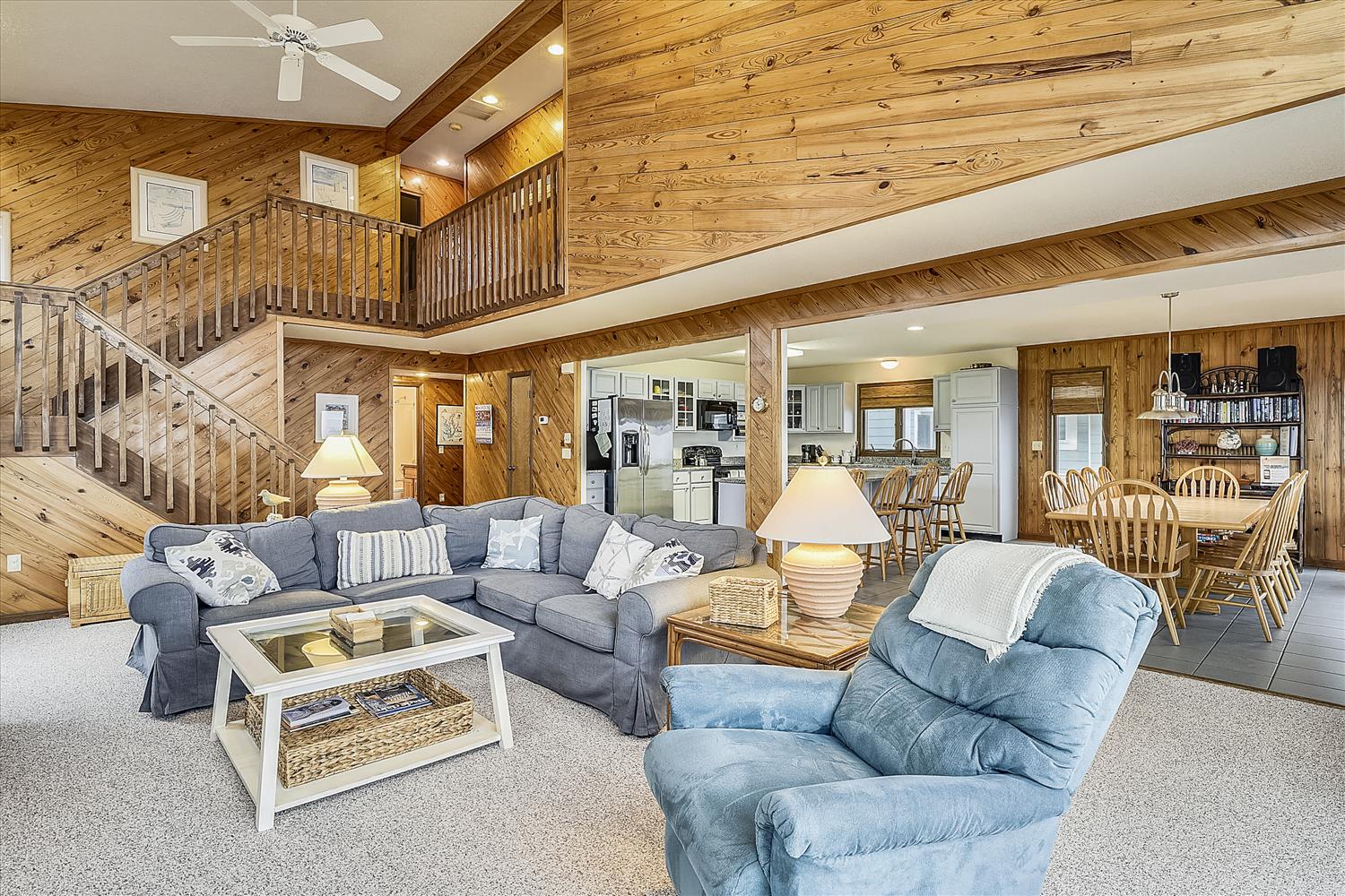 Relax in this spacious open-concept living area where warm wood beams create a cozy cabin atmosphere while you unwind on comfortable seating.