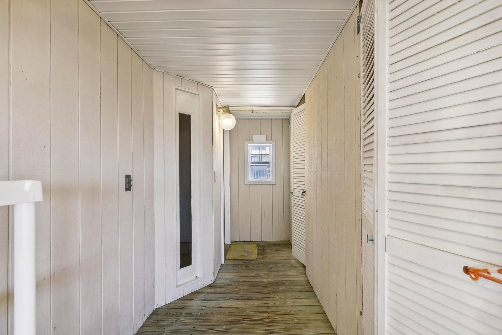 This charming hallway with whitewashed wood paneling and warm natural light connects your living spaces with a relaxed coastal cottage feel.