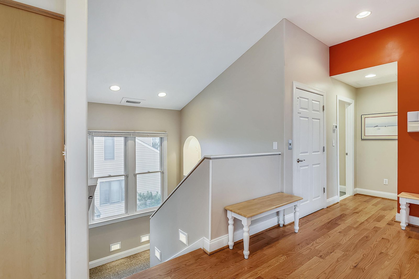 Bright hallway with warm wood floors, accent walls, and a cozy bench—your comfortable retreat for the whole trip.