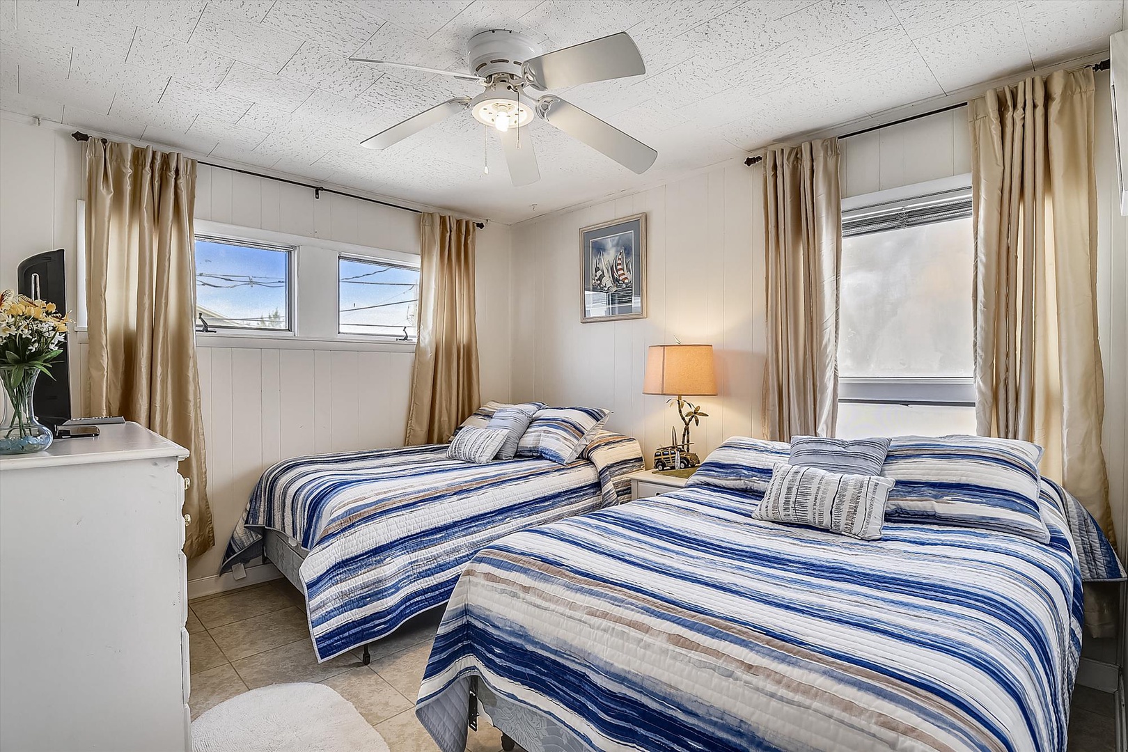 Settle into comfort in your cozy bedroom with two plush beds, soft natural light, and a ceiling fan keeping you cool after a day exploring the area.