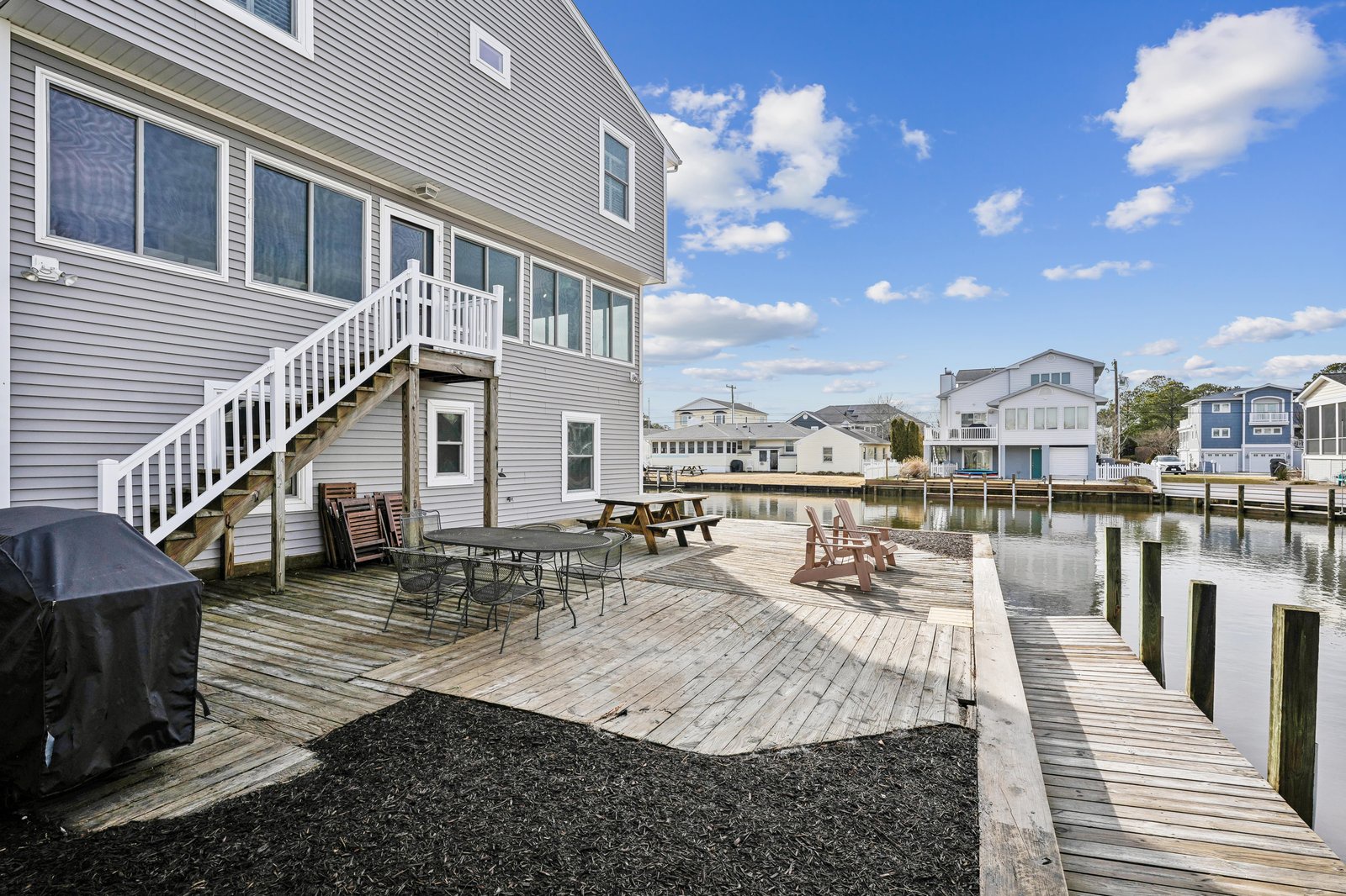 Waterfront property featuring a spacious wooden deck with private dock access, perfect for boat enthusiasts and canal-side relaxation in a peaceful residential setting.