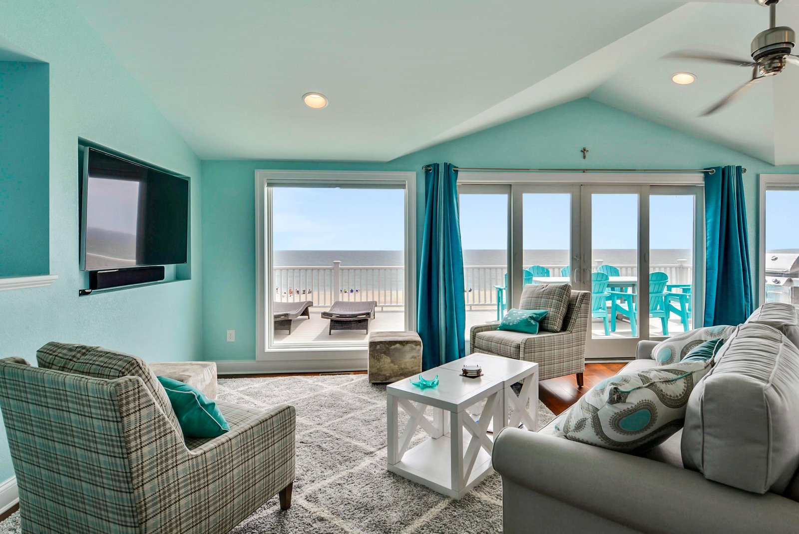 Step into your bright, breezy living room where turquoise accents echo the ocean just beyond your balcony. Sink into plush seating, let the sea breeze drift through open doors, and make yourself at home in this coastal retreat.