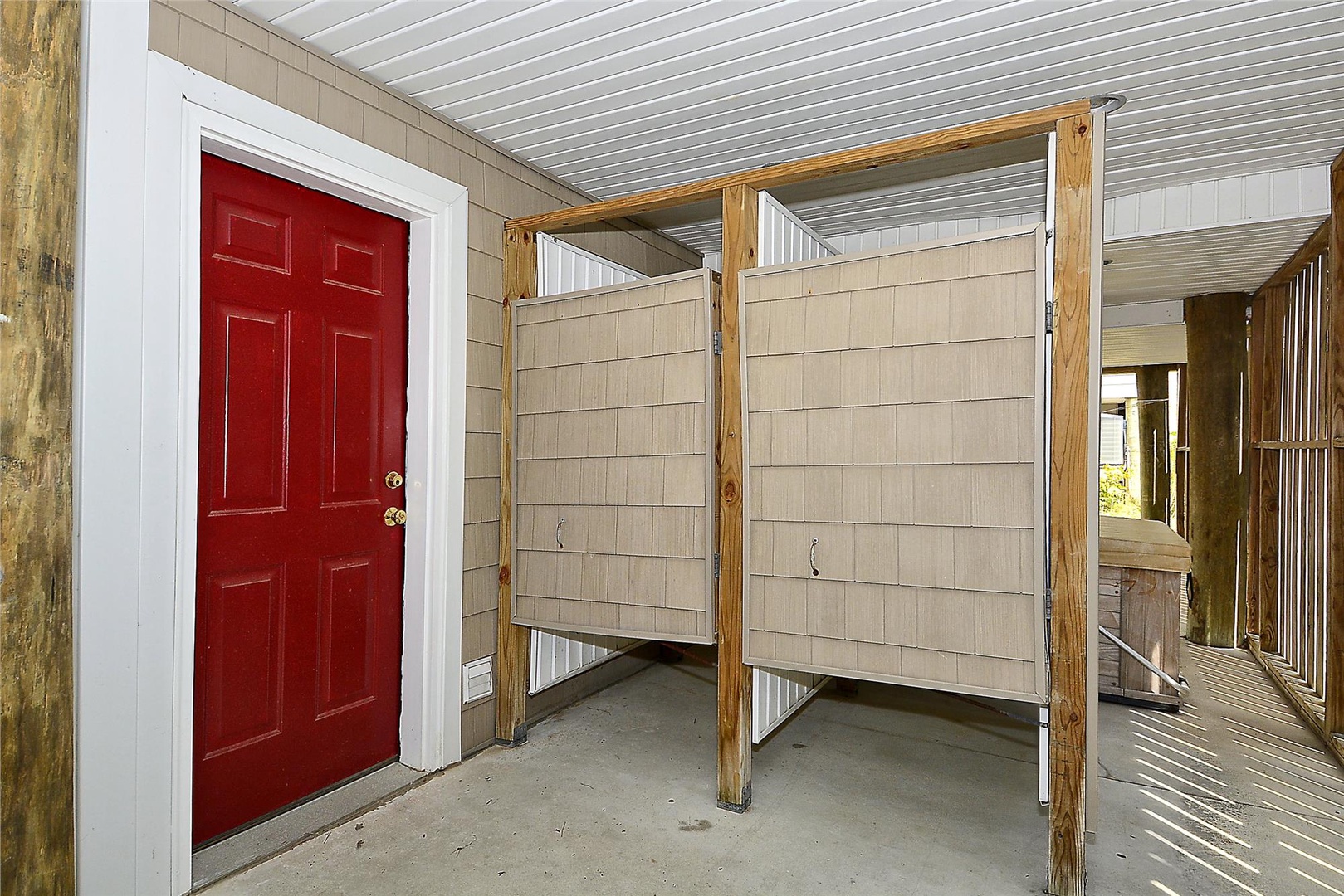 A covered entrance with a bright red door welcomes you, with convenient outdoor storage cubbies for your beach gear and a shaded, protected area perfect for storing bikes and equipment.