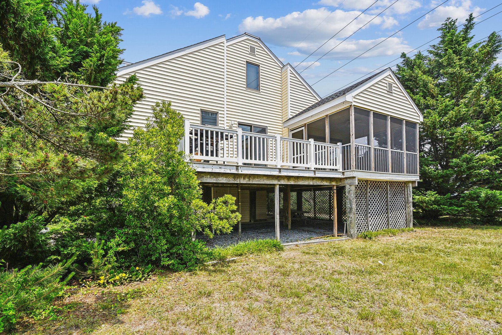 Charming two-story coastal retreat set among lush greenery, with spacious deck and screened porch for enjoying the tranquil surroundings and coastal breeze.