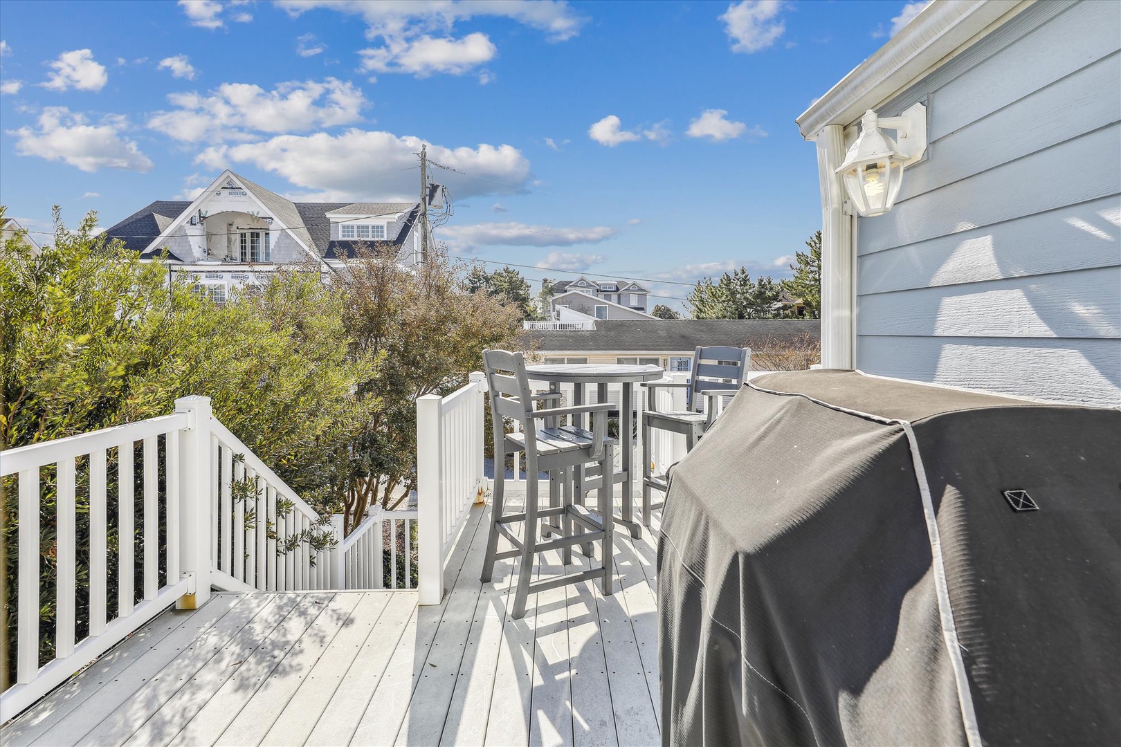 Private deck with high-top seating and covered grill, offering a peaceful spot to enjoy fresh air and neighborhood views.