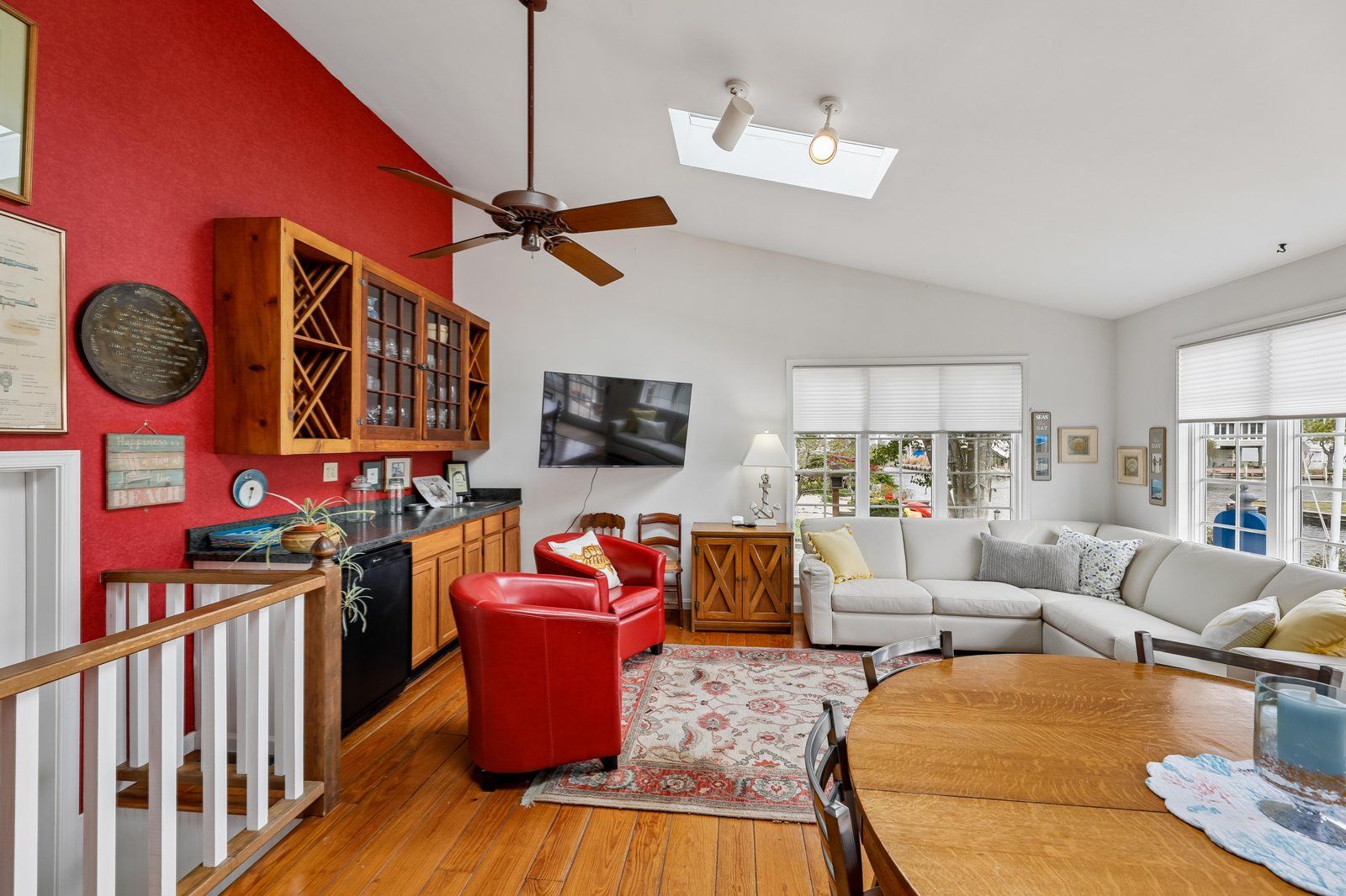 Relax in your bright open living area where bold red accents meet cozy seating, gleaming wood floors, and a wet bar ready for entertaining. Natural light pours in through large windows that frame neighborhood views.