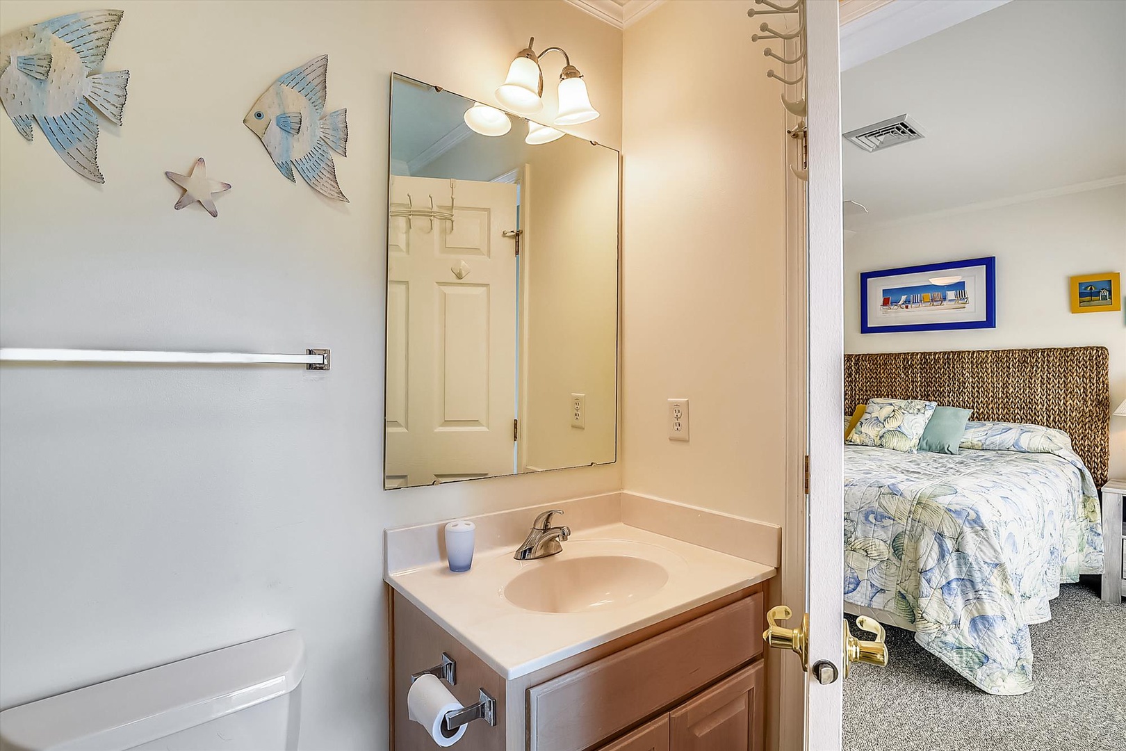 Coastal-themed bathroom with beach decor connects to your comfortable sleeping space, featuring a woven headboard and bright accents for a relaxing coastal retreat vibe.