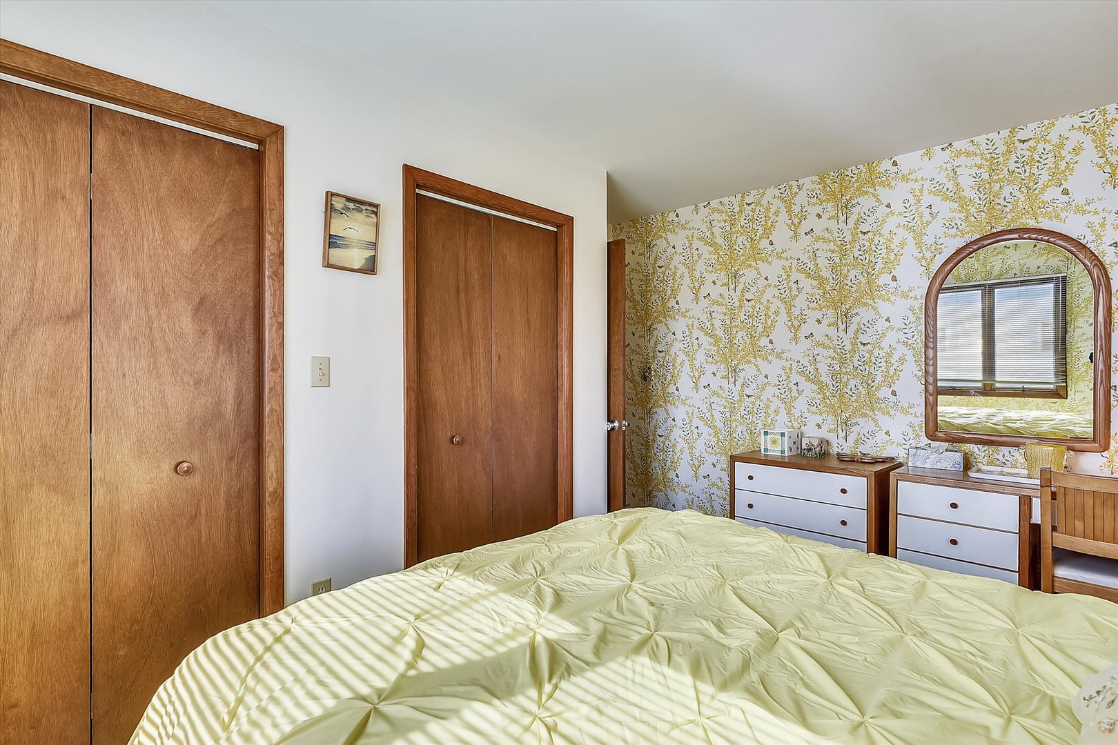 Wake up refreshed in your cozy bedroom, featuring charming vintage wallpaper and plenty of storage. Sunlight streams through the window, inviting you to start your day in this peaceful retreat.