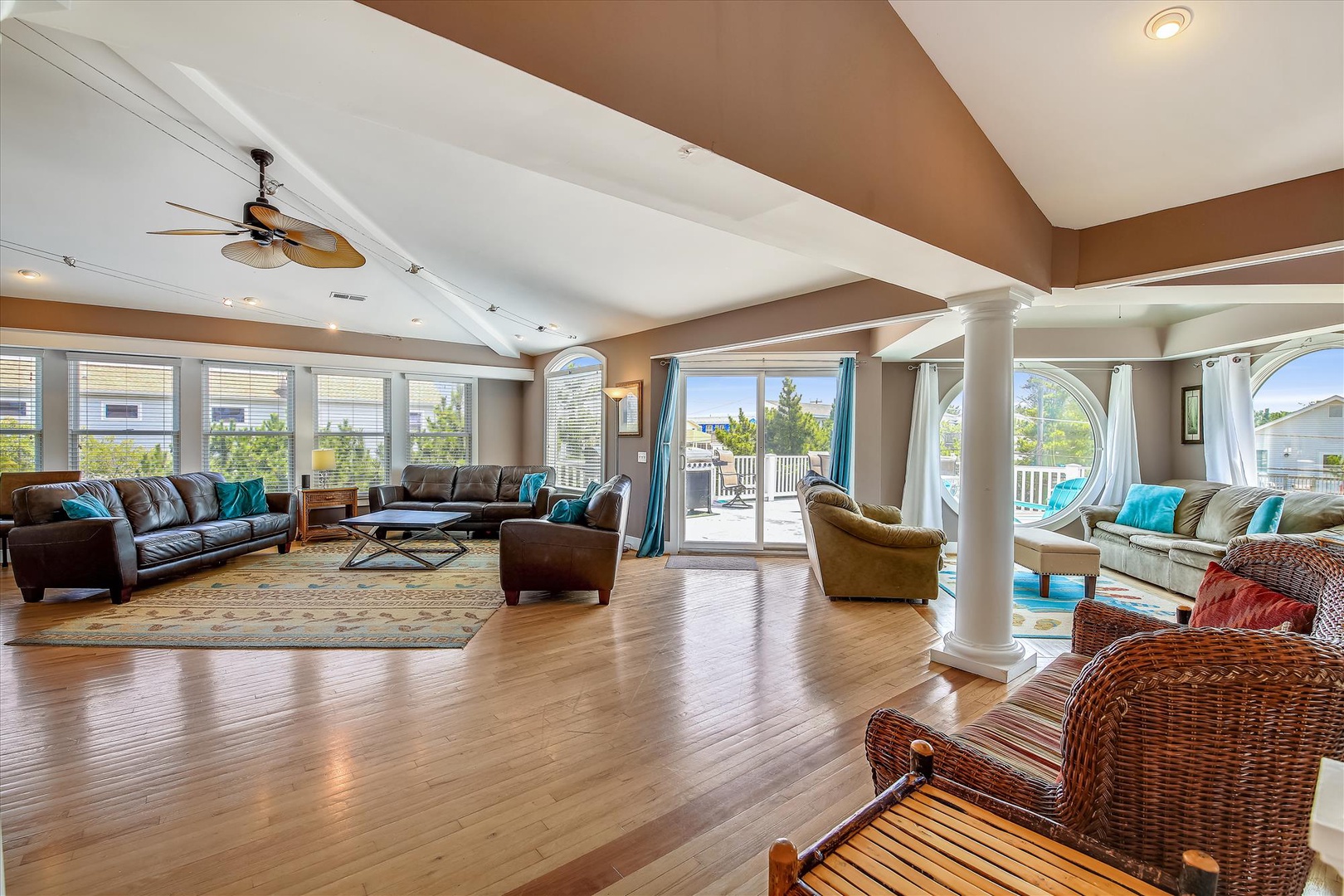 Gather in this bright, spacious living area where gleaming hardwood floors and vaulted ceilings create an airy atmosphere. Sink into plush seating while sunlight streams through expansive windows.
