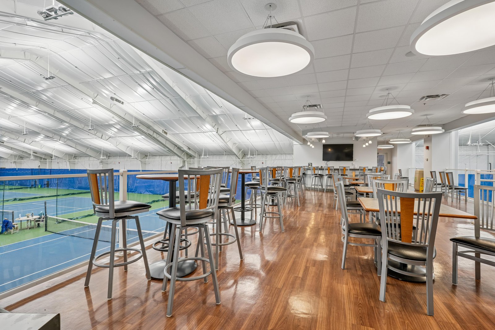 Indoor tennis courts feature a spectator lounge with comfortable seating, perfect for watching matches or relaxing between games.