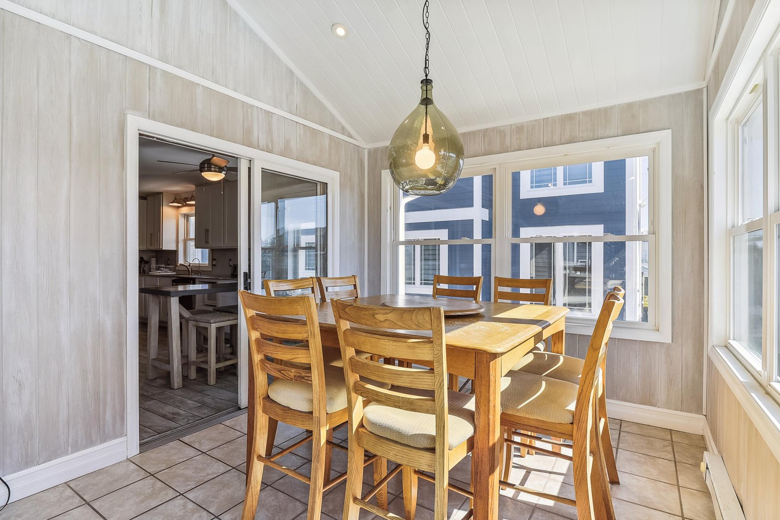 Gather around the warm wood dining table under charming vintage lighting, with bright windows framing your beachside neighborhood and the kitchen just steps away.