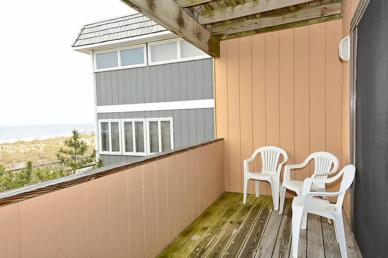 A small covered balcony with two white chairs overlooks the sea and dunes, offering a perfect spot to relax with your morning coffee or watch the evening light shift over the water.