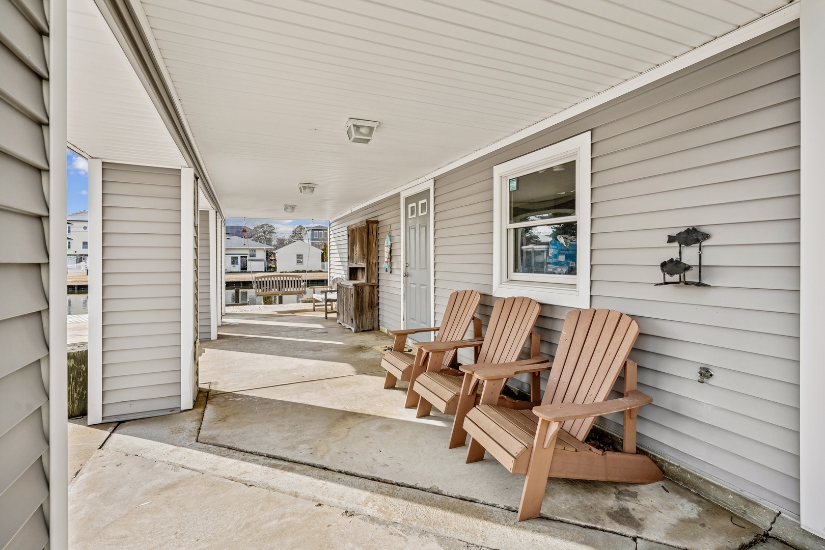 Relax on your private covered patio with comfortable Adirondack chairs, perfect for morning coffee or evening conversations in this peaceful residential setting.