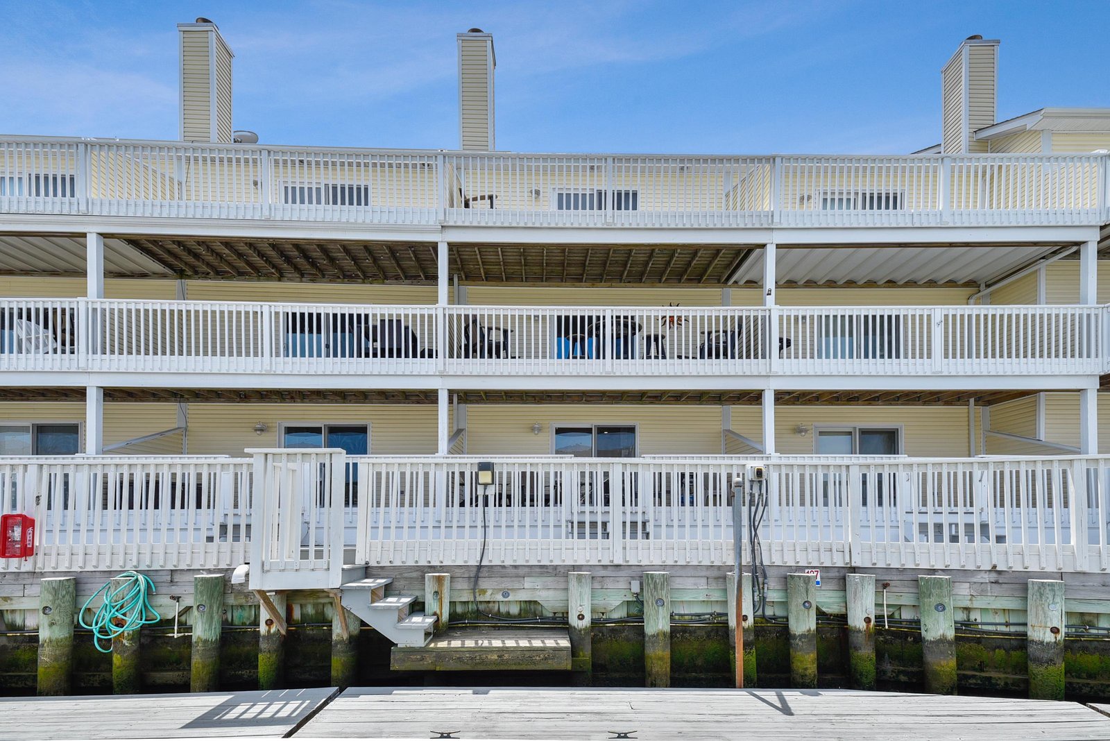 Multi-level waterfront vacation property featuring yellow siding and private balconies with direct dock access.