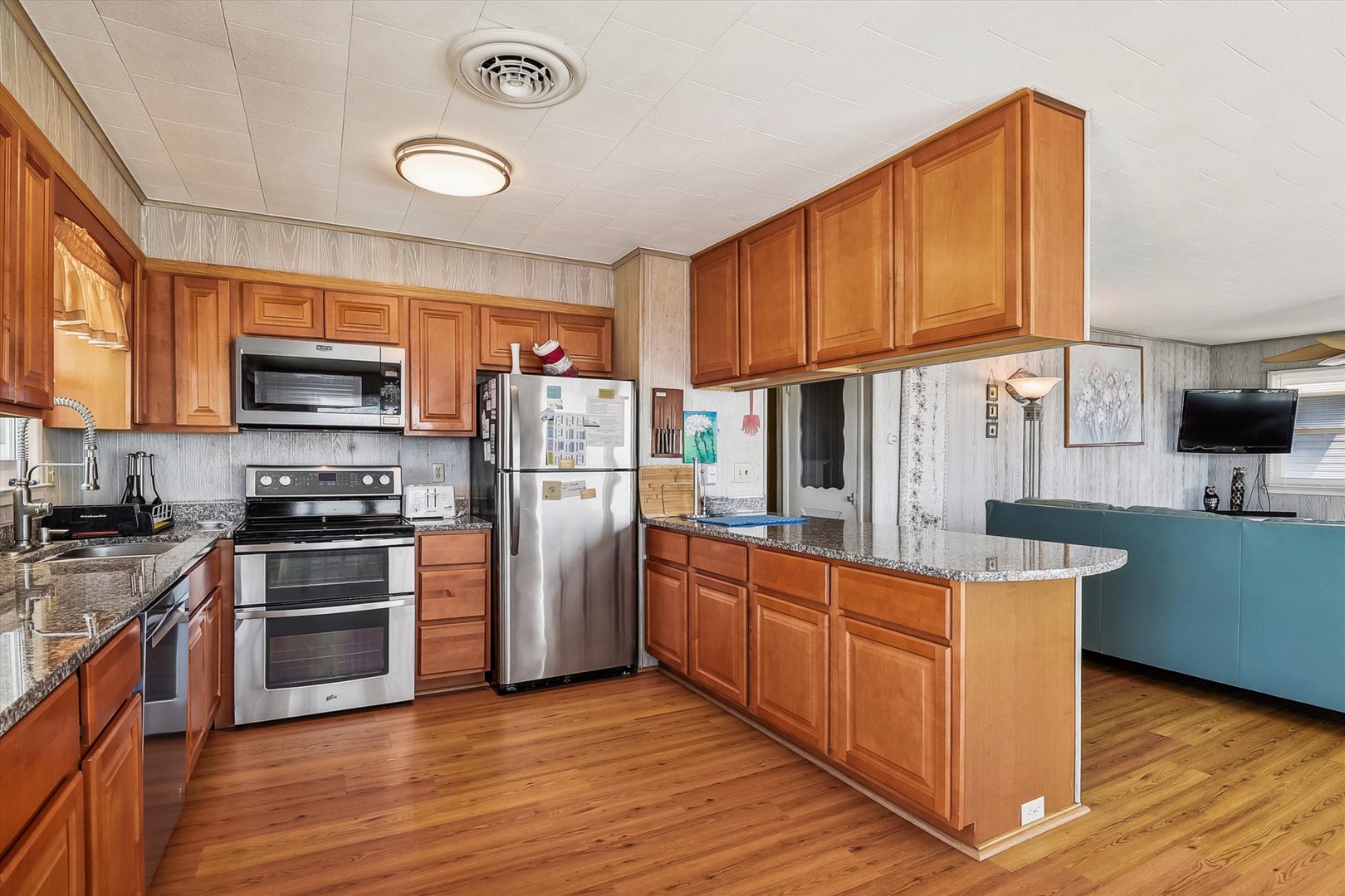 Your fully equipped kitchen features gleaming granite countertops, rich wood cabinetry, and modern stainless steel appliances—perfect for preparing meals or enjoying casual dining at the bar.