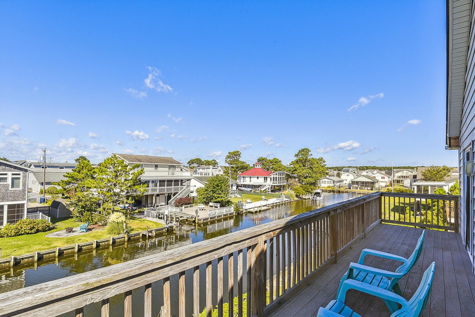 A peaceful waterfront neighborhood with canal access, green lawns, private docks, and nearby homes nestled among mature trees beneath a clear blue sky.