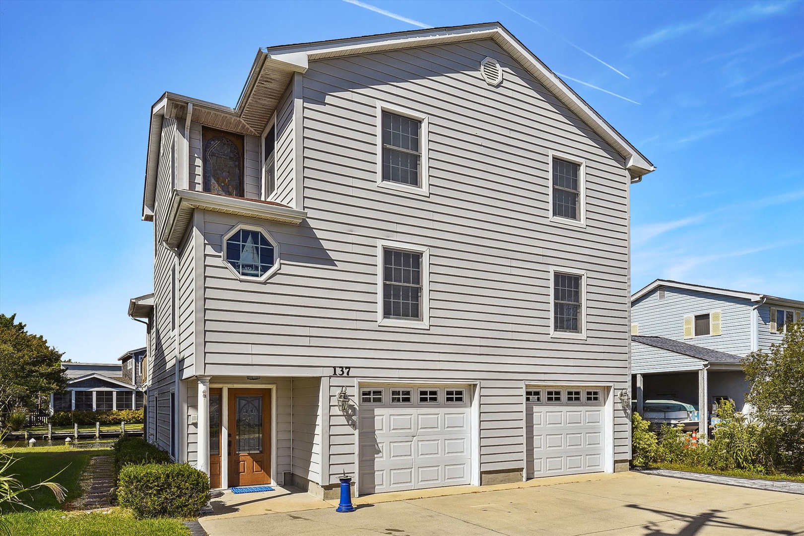Multi-level coastal property with light gray siding, residential neighborhood setting, and convenient garage parking.