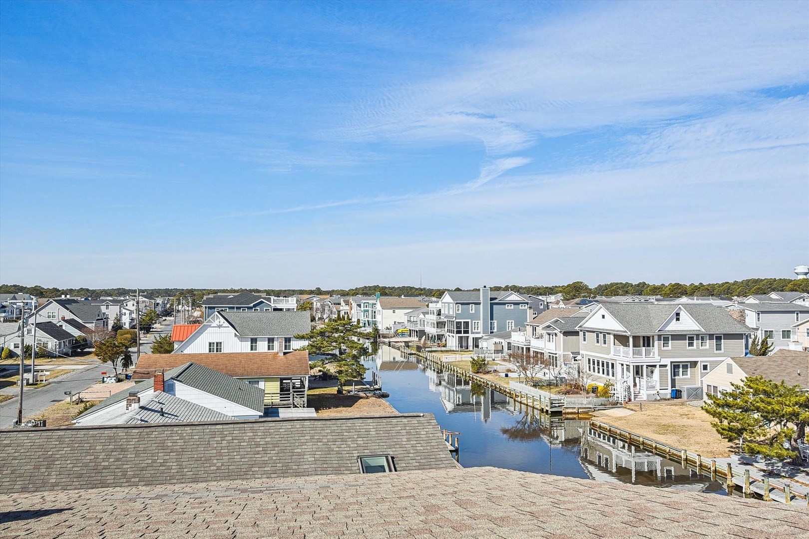 Elevated view of a charming waterfront community with canal homes, private docks, and coastal architecture under blue skies.