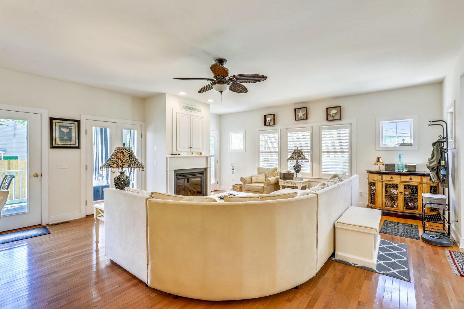 Sink into the spacious curved sofa and let the coastal breeze from the ceiling fan wash over you. Warm wood floors, soft lighting, and a cozy fireplace invite you to unwind in your home away from home.