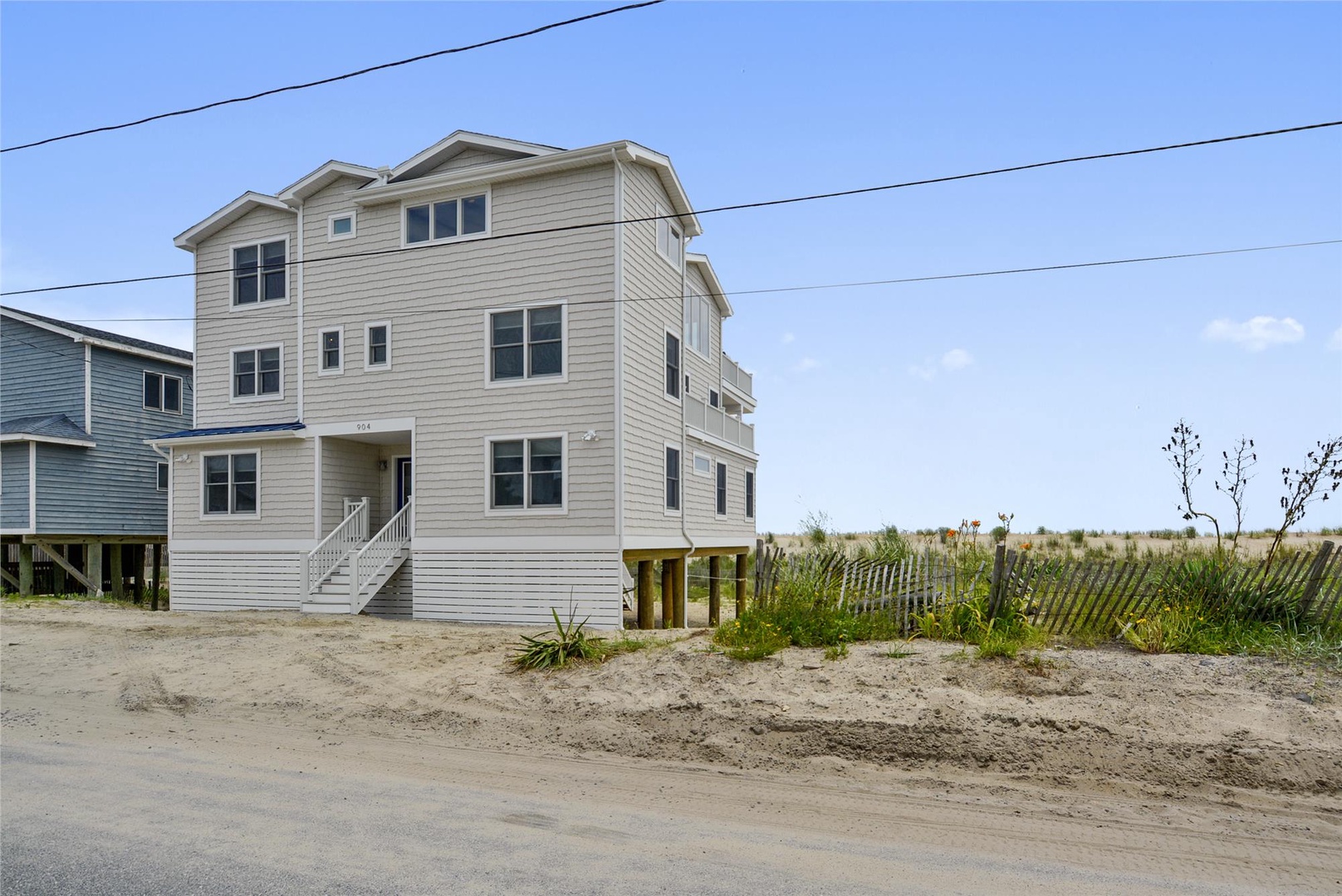 Spacious beachfront property situated on sandy terrain with direct access to the shore and coastal dunes, offering a prime location for seaside relaxation and easy beach entry.