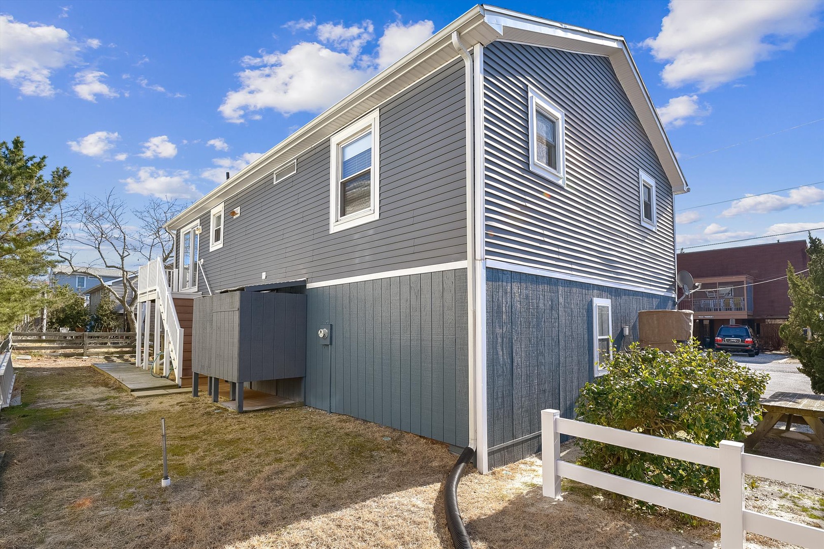 Modern elevated coastal property with gray siding, white trim, and ample natural light. Located in a quiet residential area with outdoor space and parking.