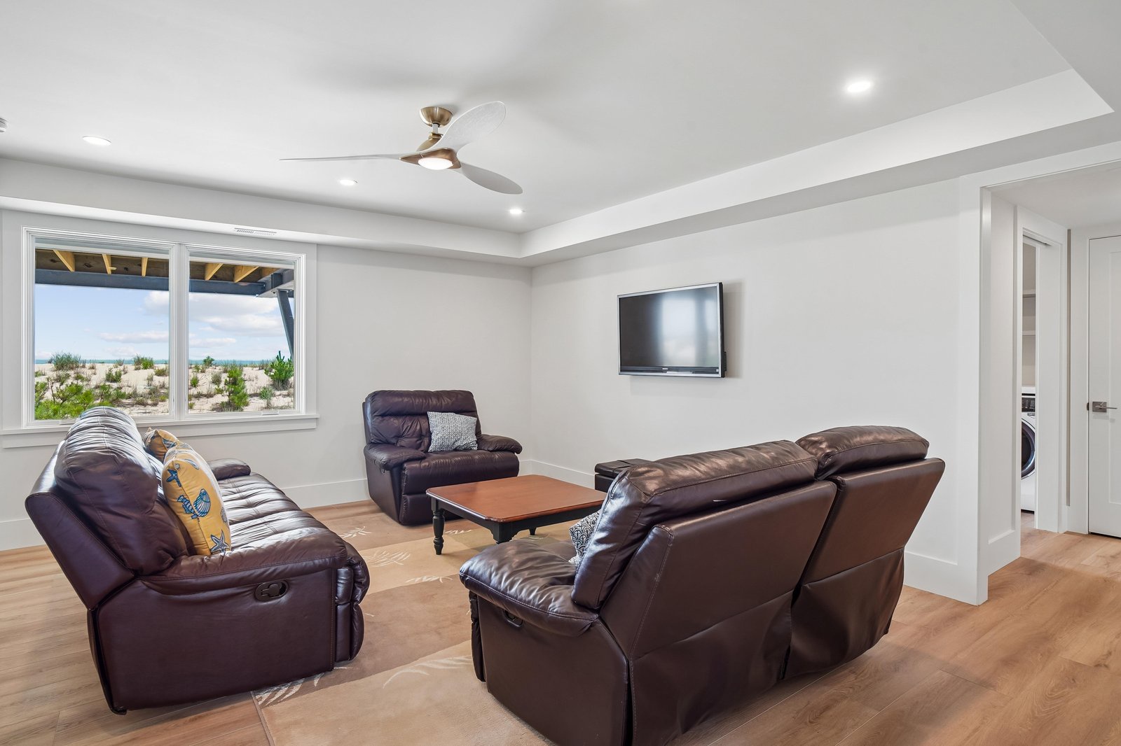 Unwind in your spacious living room with plush leather seating and a ceiling fan to keep you cool, while natural light spills in through large windows framing peaceful desert views.